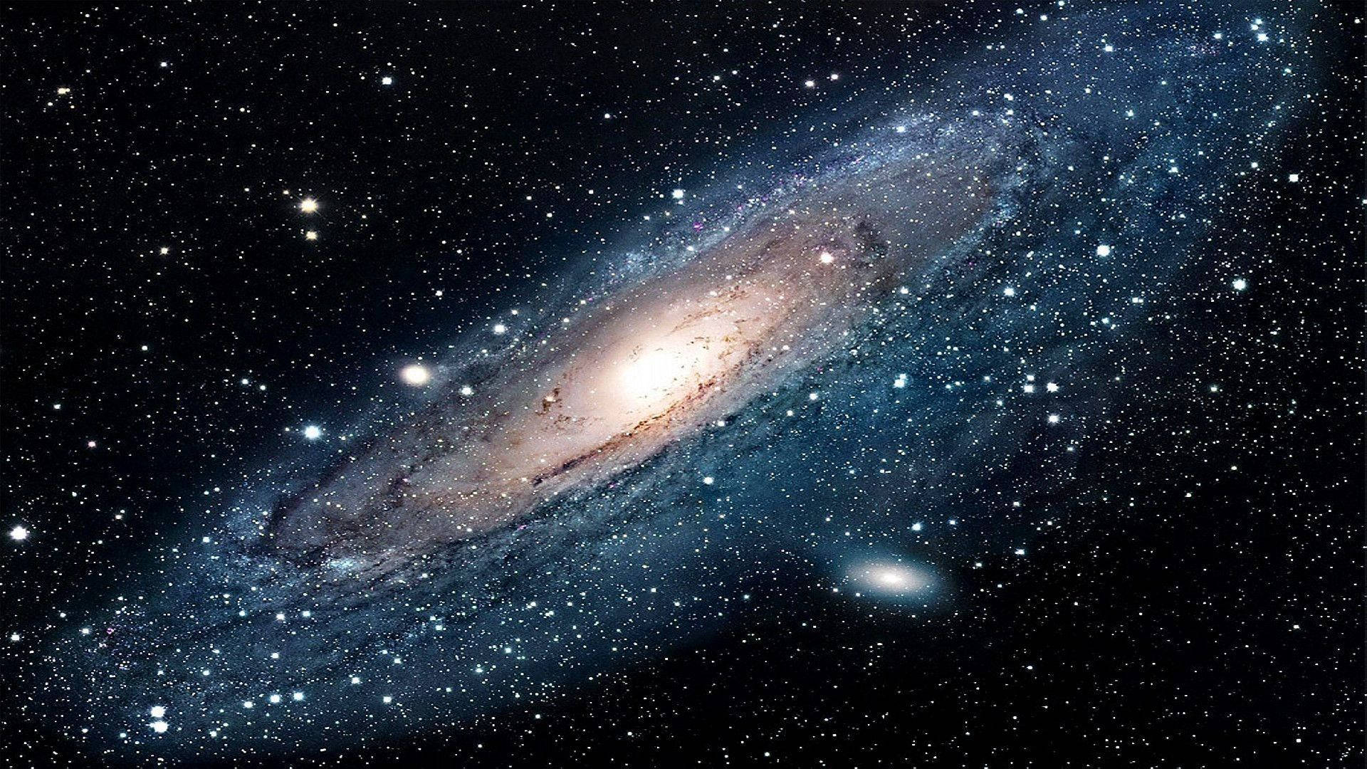 Stars 桌布 壁紙 — 一個宏偉的螺旋星系在深空的星場中閃耀著藍色和金色的色調。