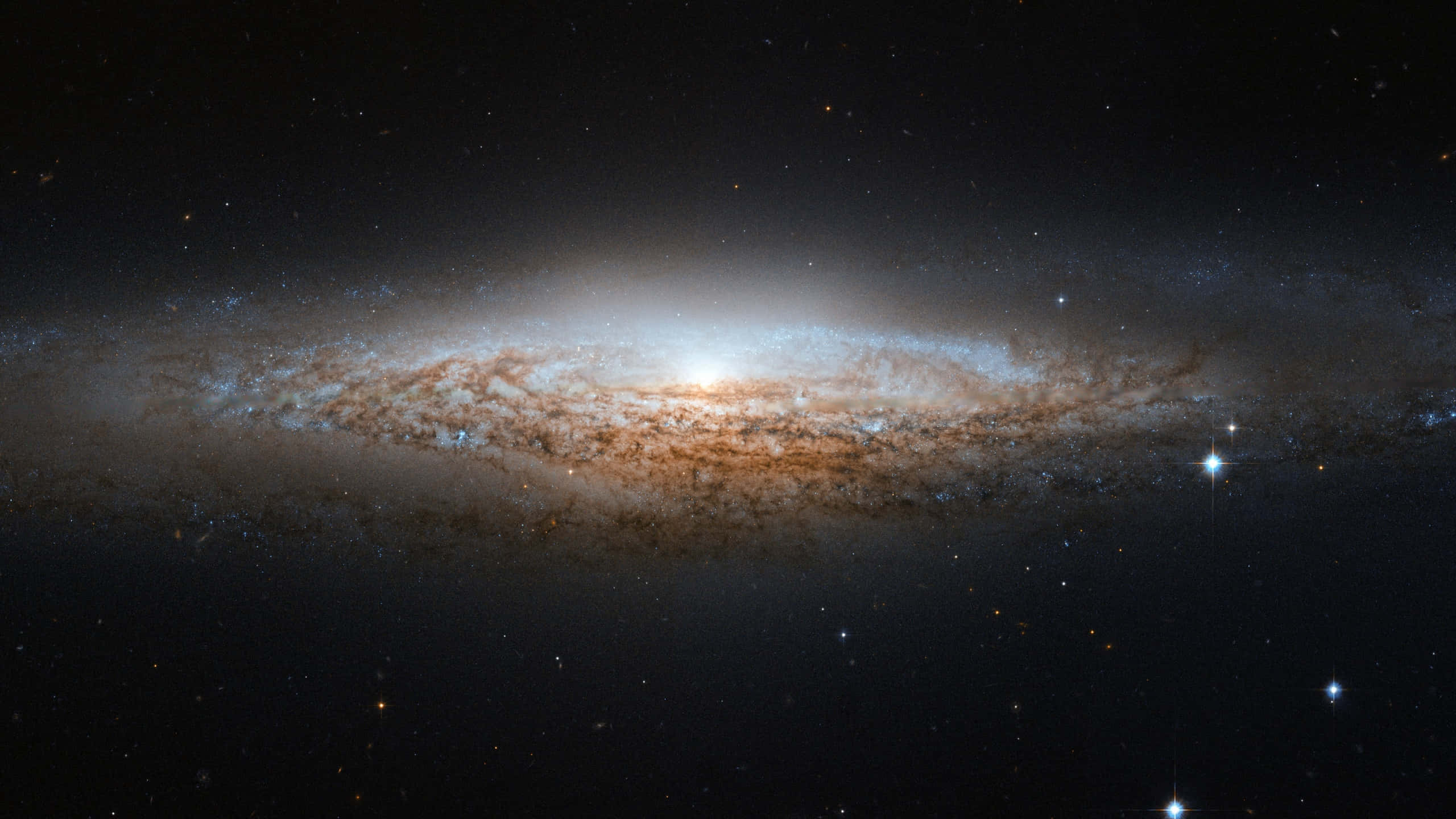 桌布 壁紙 — 一個宏偉的螺旋星系在繁星點點的宇宙背景下閃耀著金色和藍色的色調。