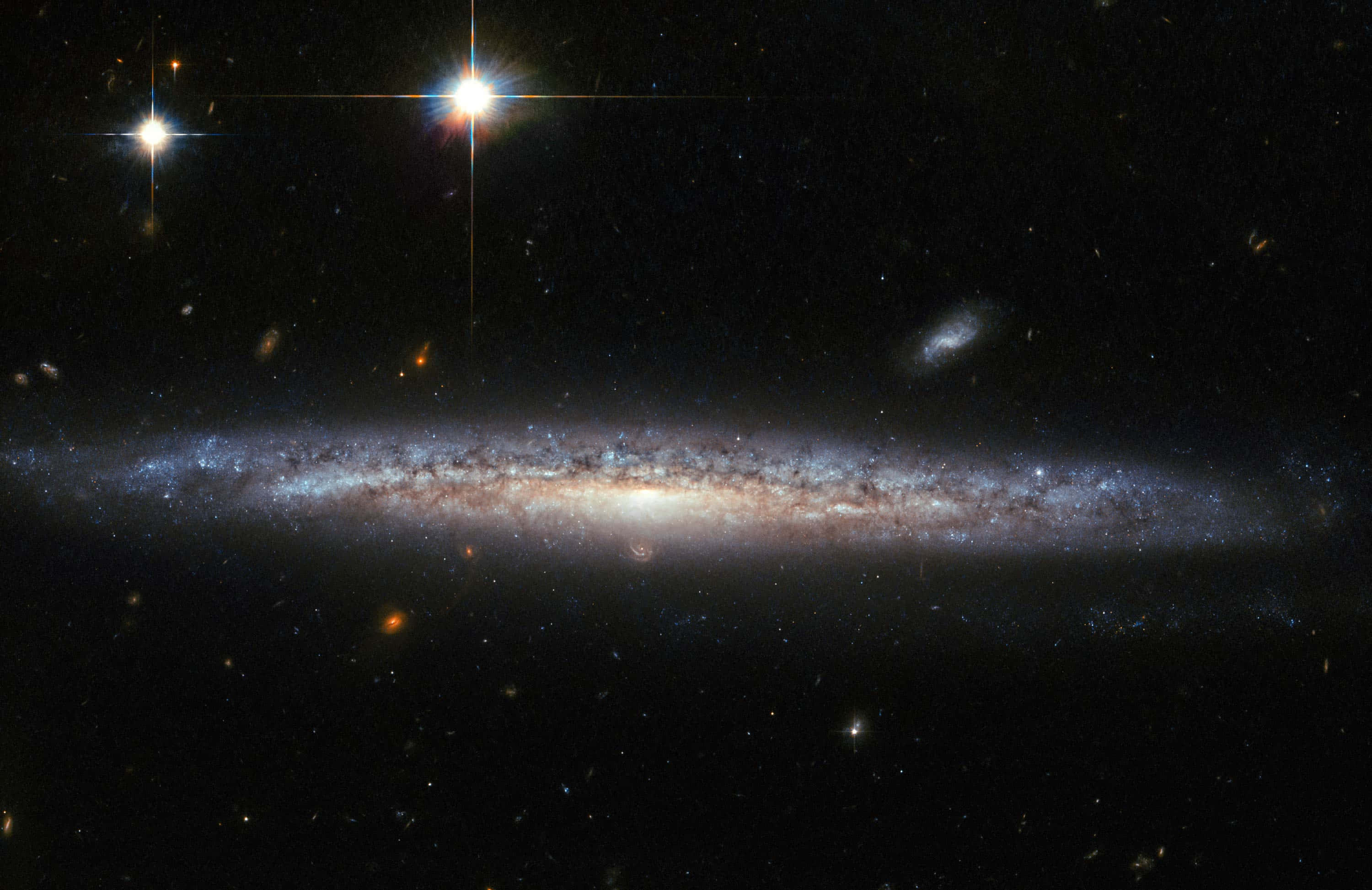 銀河 桌布 壁紙 — 一個宏偉的螺旋星系橫跨宇宙，發出藍色和橙色的光芒，周圍環繞著閃爍的星星和遙遠的宇宙雲。