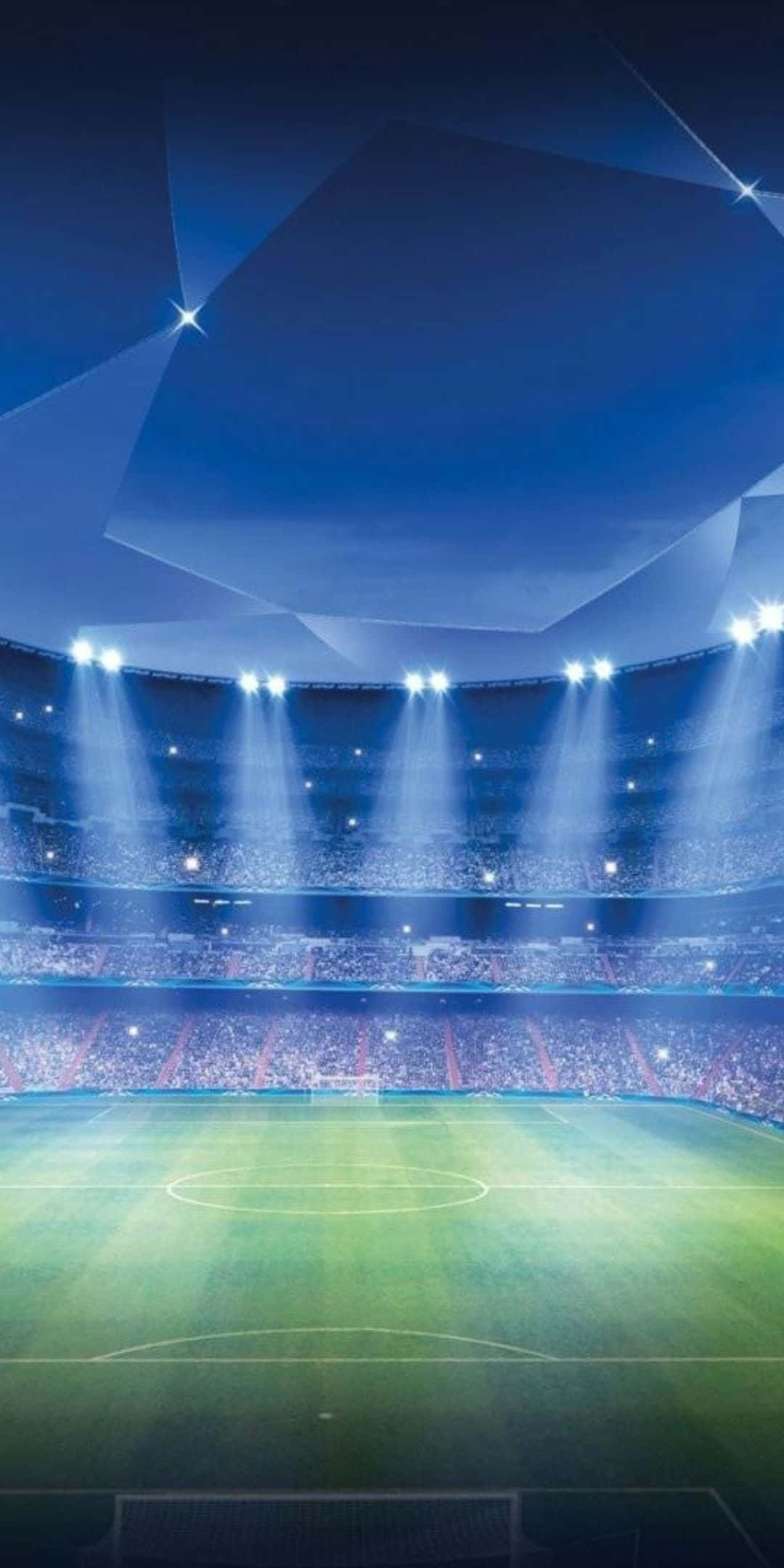 Football Field 桌布 壁紙 — 一個宏偉的足球場，沐浴在戲劇性的藍色燈光中，聚光燈照亮了充滿活力的綠色球場和擠滿觀眾的看台。