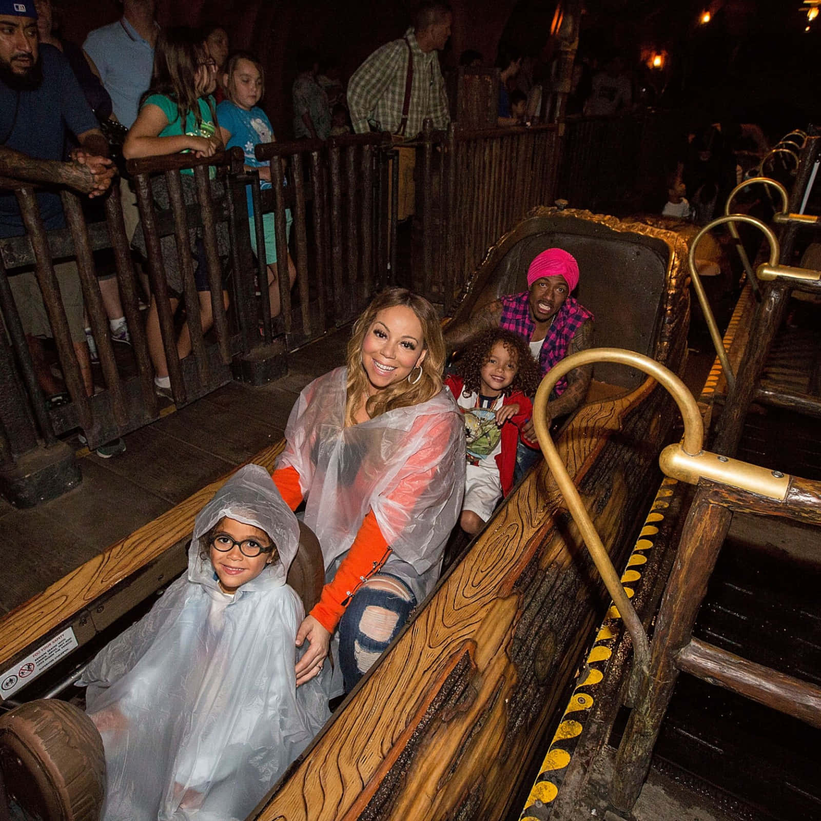 Splash Mountain 桌布 壁紙 — 一個家庭穿著透明雨衣，在主題公園的深色木製激流滑道上開心地微笑。