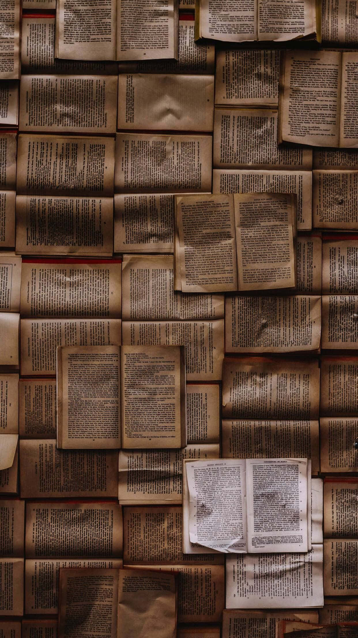 books 桌布 壁紙 — 一個密集的馬賽克，由發黃書頁和褪色文字的古老打開書籍組成，營造出有紋理的文學牆。
