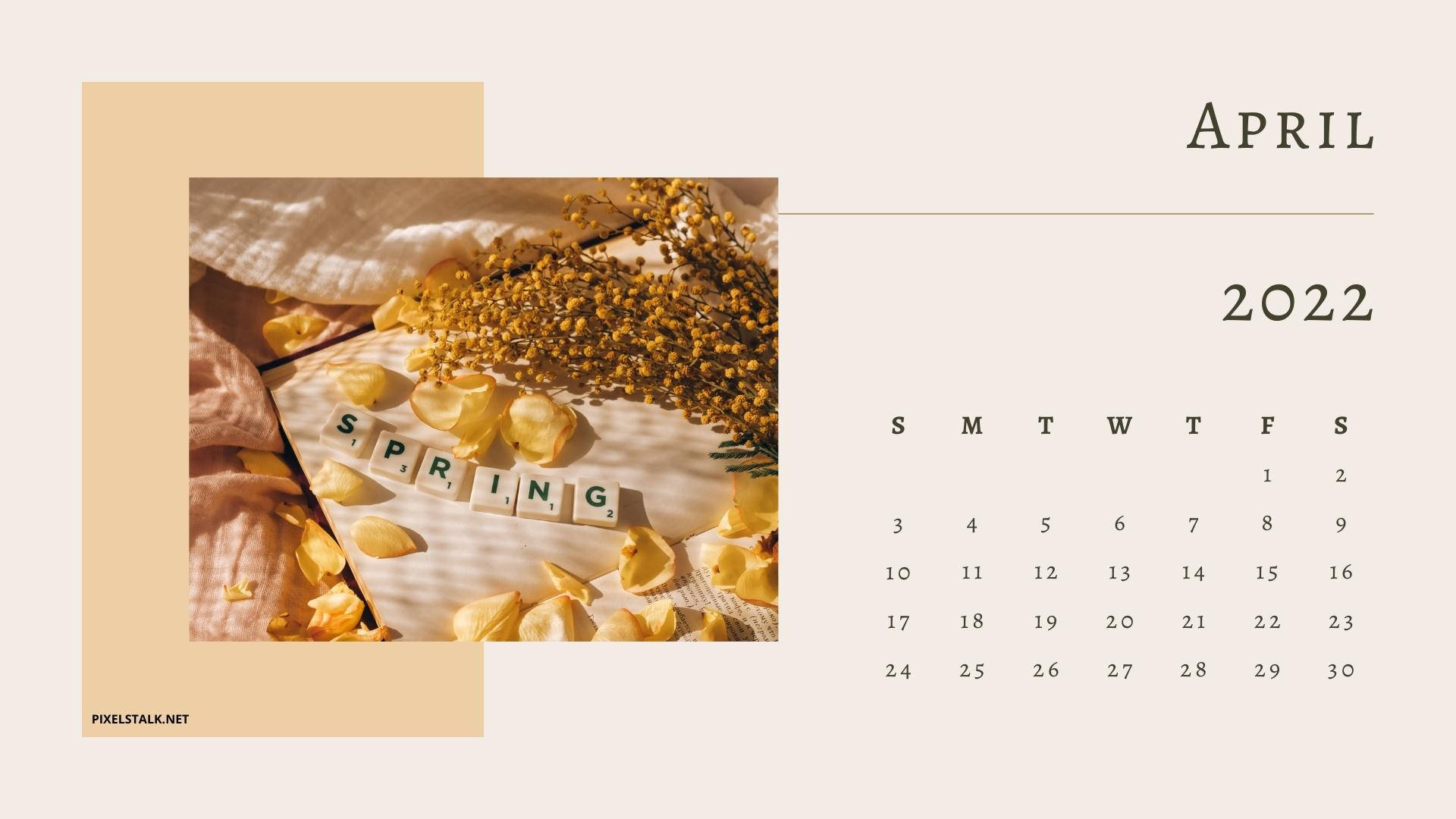 春天 桌布 壁紙 — 一個寧靜的2022年4月月曆，用木製瓷磚拼出「SPRING」，周圍環繞著黃色花瓣和乾花，放在有紋理的布料上。