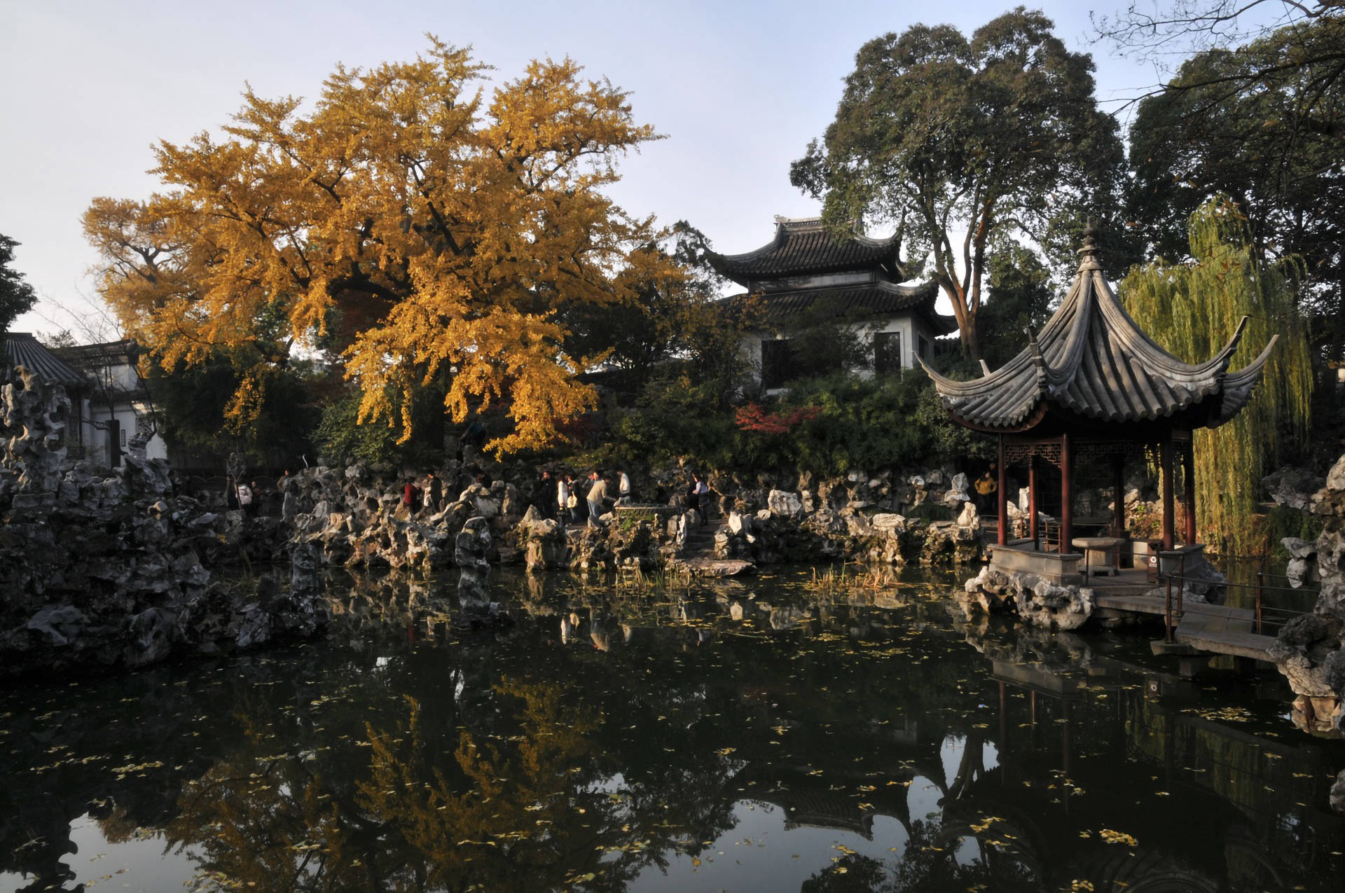 Suzhou 桌布 壁紙 — 一個寧靜的傳統中式花園池塘，在柔和秋光下倒映著金色的銀杏樹和華麗的亭台樓閣。