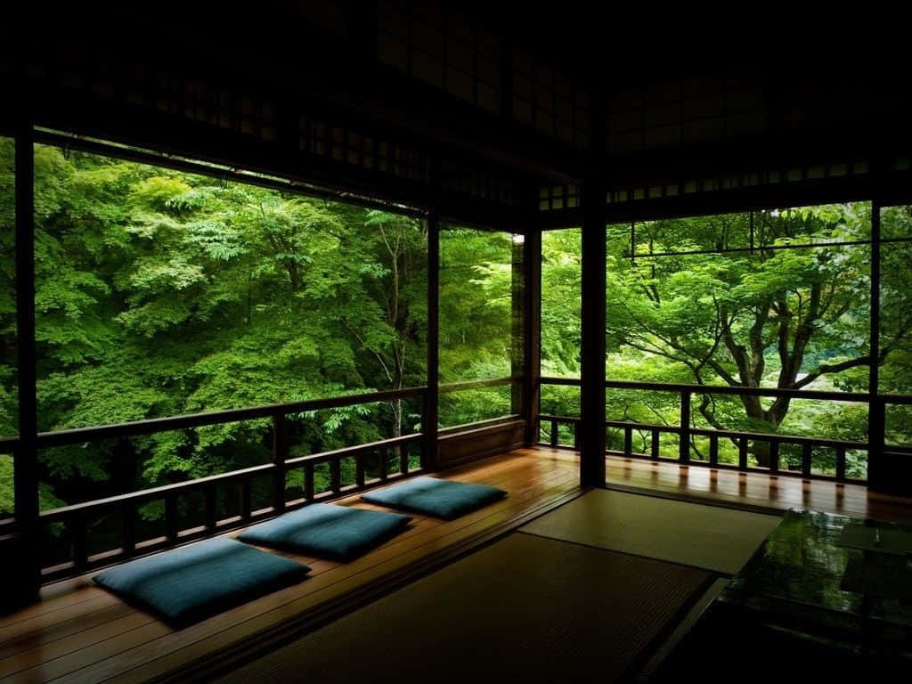 禪 桌布 壁紙 — 一個寧靜的傳統日式房間，鋪有木地板和藍色坐墊，俯瞰著沐浴在柔和自然光線下的茂密綠色森林。
