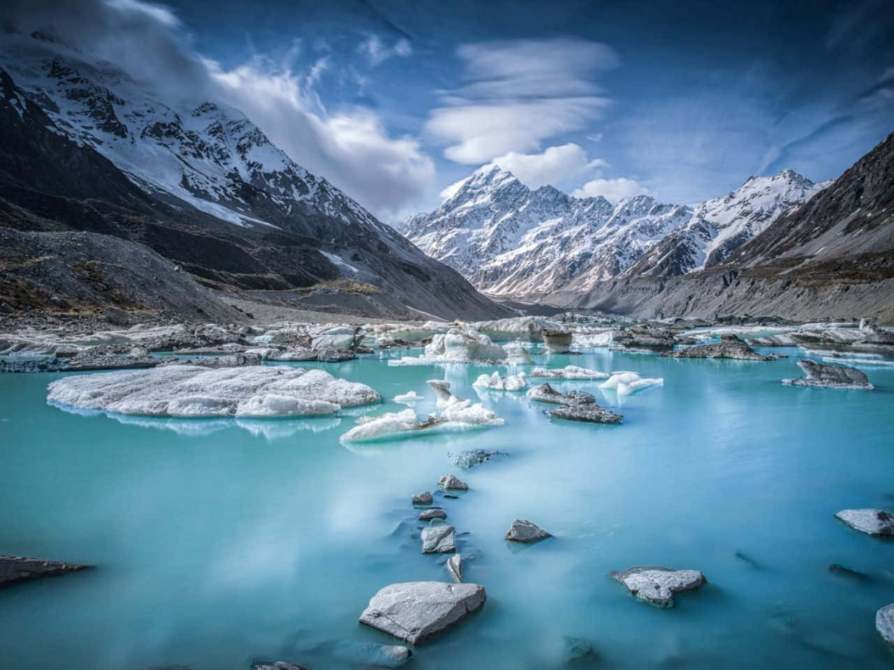 1280x960 桌布 壁紙 — 一個寧靜的冰川湖，湖水碧綠，漂浮著冰山，四周被白雪覆蓋的山脈環繞，天空壯麗。