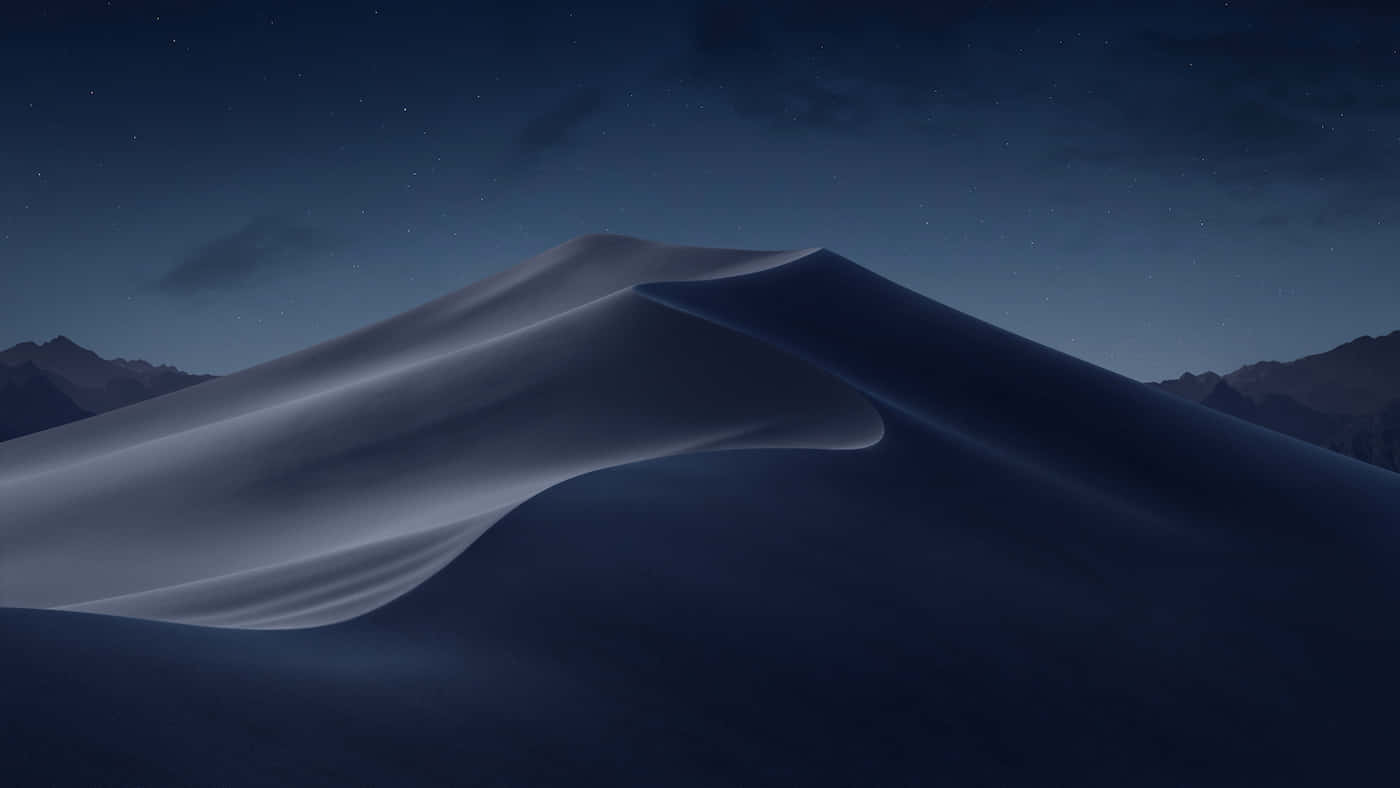 Desert 桌布 壁紙 — 一個寧靜的夜晚場景，平滑起伏的沙丘在星空下，遠方有山脈。