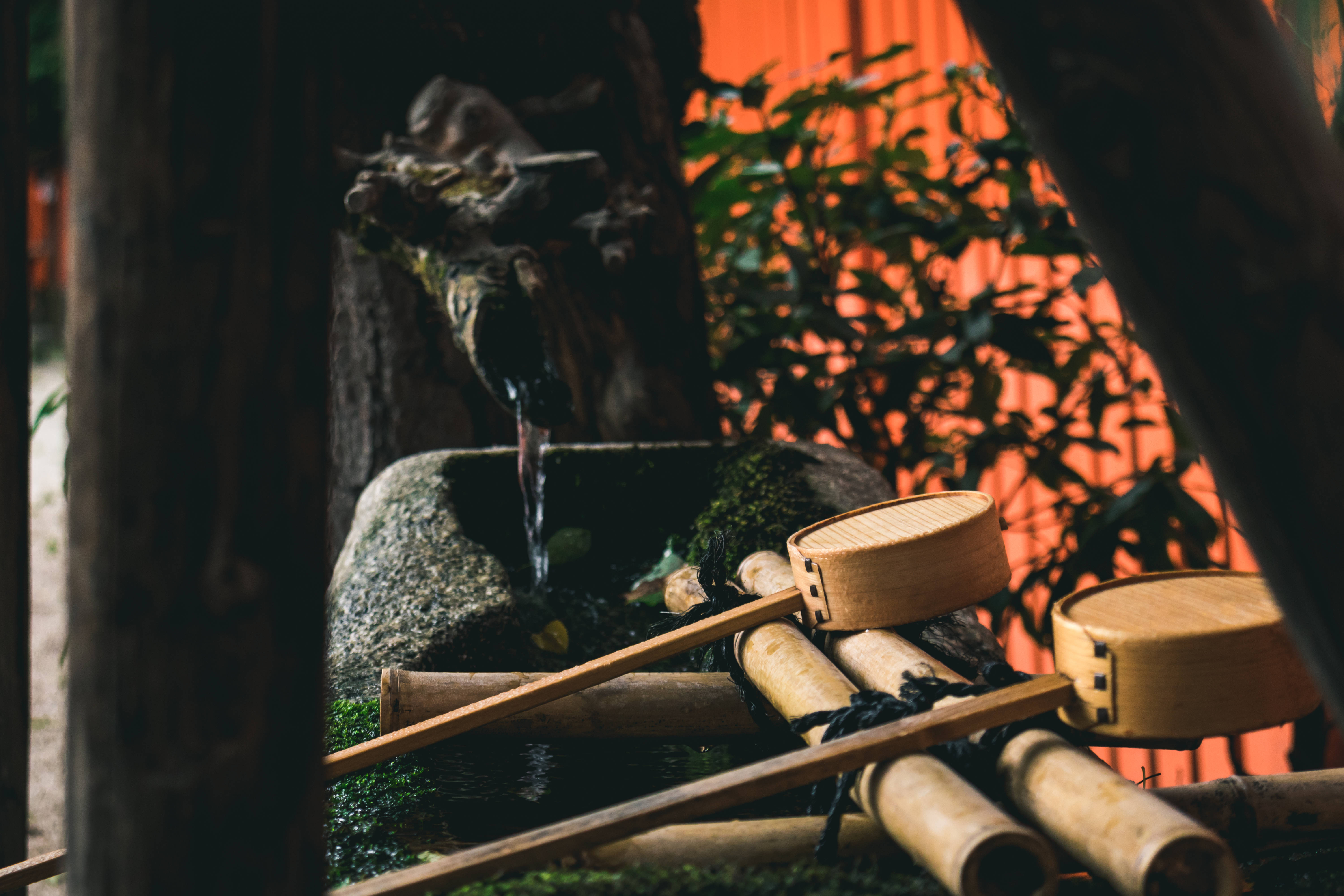 Bamboo HD 桌布 壁紙 — 一個寧靜的日本石水泉，配有竹勺和苔蘚，在溫暖的橙色燈光下。