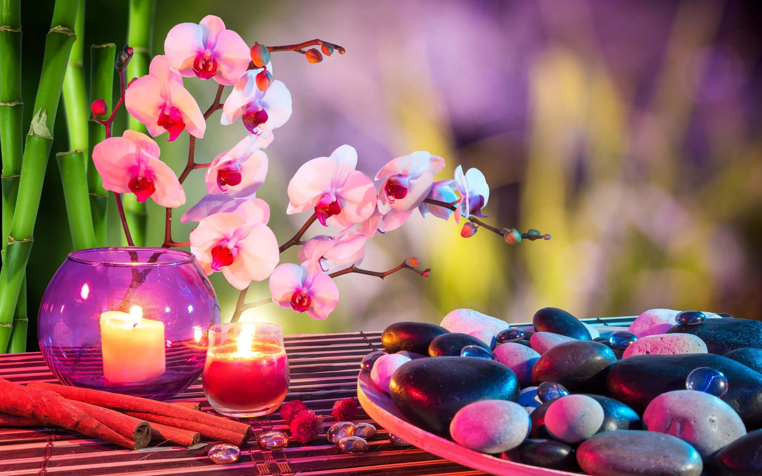 禪 桌布 壁紙 — 一個寧靜的水療場景，粉紅色的蘭花、發光的蠟燭和光滑的石頭放在竹蓆上，在柔和的紫色燈光下。