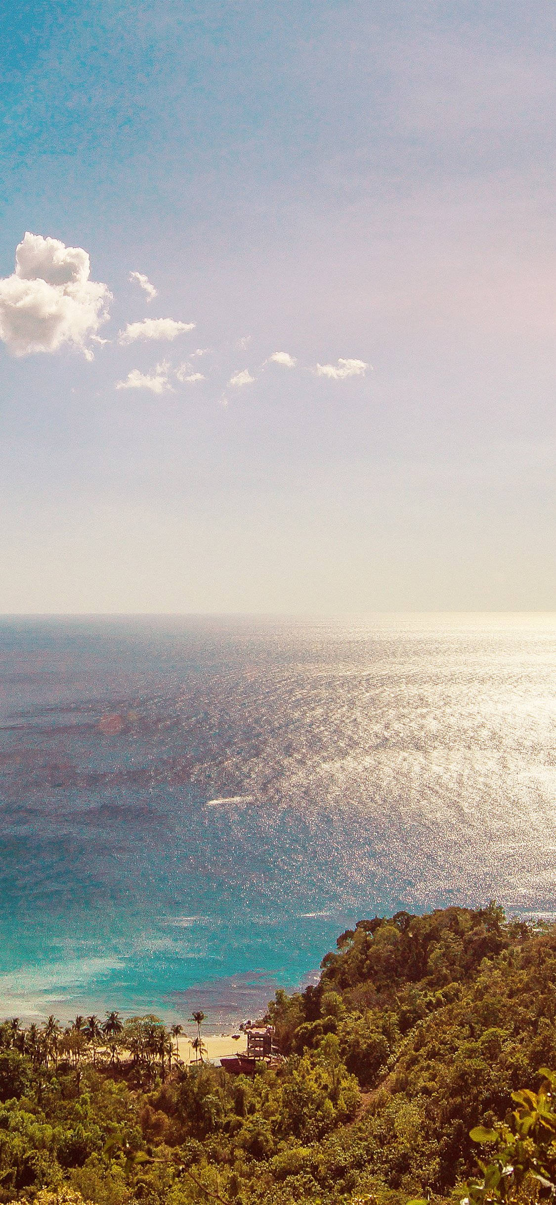 海洋 桌布 壁紙 — 一個寧靜的熱帶海灘，擁有碧綠的海水和茂密的綠色山丘，在柔和藍天和零星雲朵下。