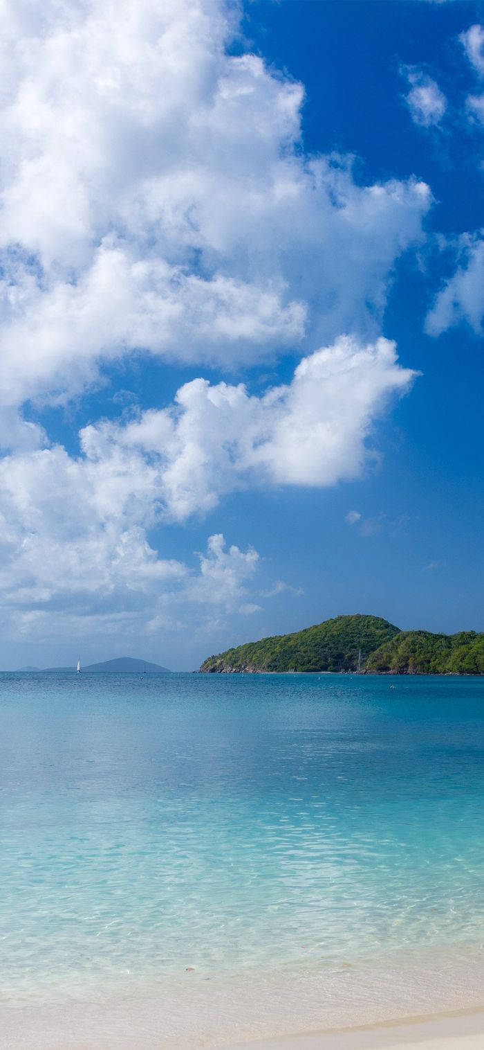 Best Summer 桌布 壁紙 — 一個寧靜的熱帶海灘，擁有碧綠的海水、溫柔的海浪和一個鬱鬱蔥蔥的綠色島嶼，在明亮的藍天下有蓬鬆的白雲。