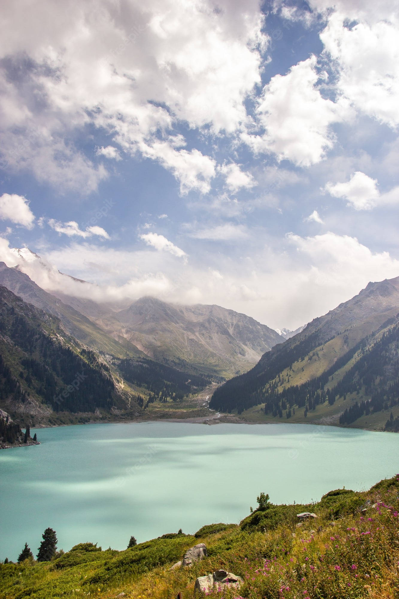 Kazakhstan 桌布 壁紙 — 一個寧靜的綠松石色山湖，坐落在山谷中，上方有白雪覆蓋的山峰和蓬鬆的白雲。