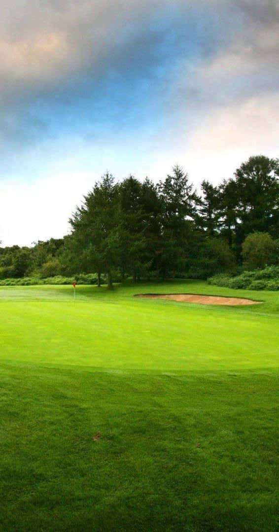 Pixel 3 Golf Course 桌布 壁紙 — 一個寧靜的高爾夫球場，擁有充滿活力的綠色球道和沙坑，天空部分多雲。