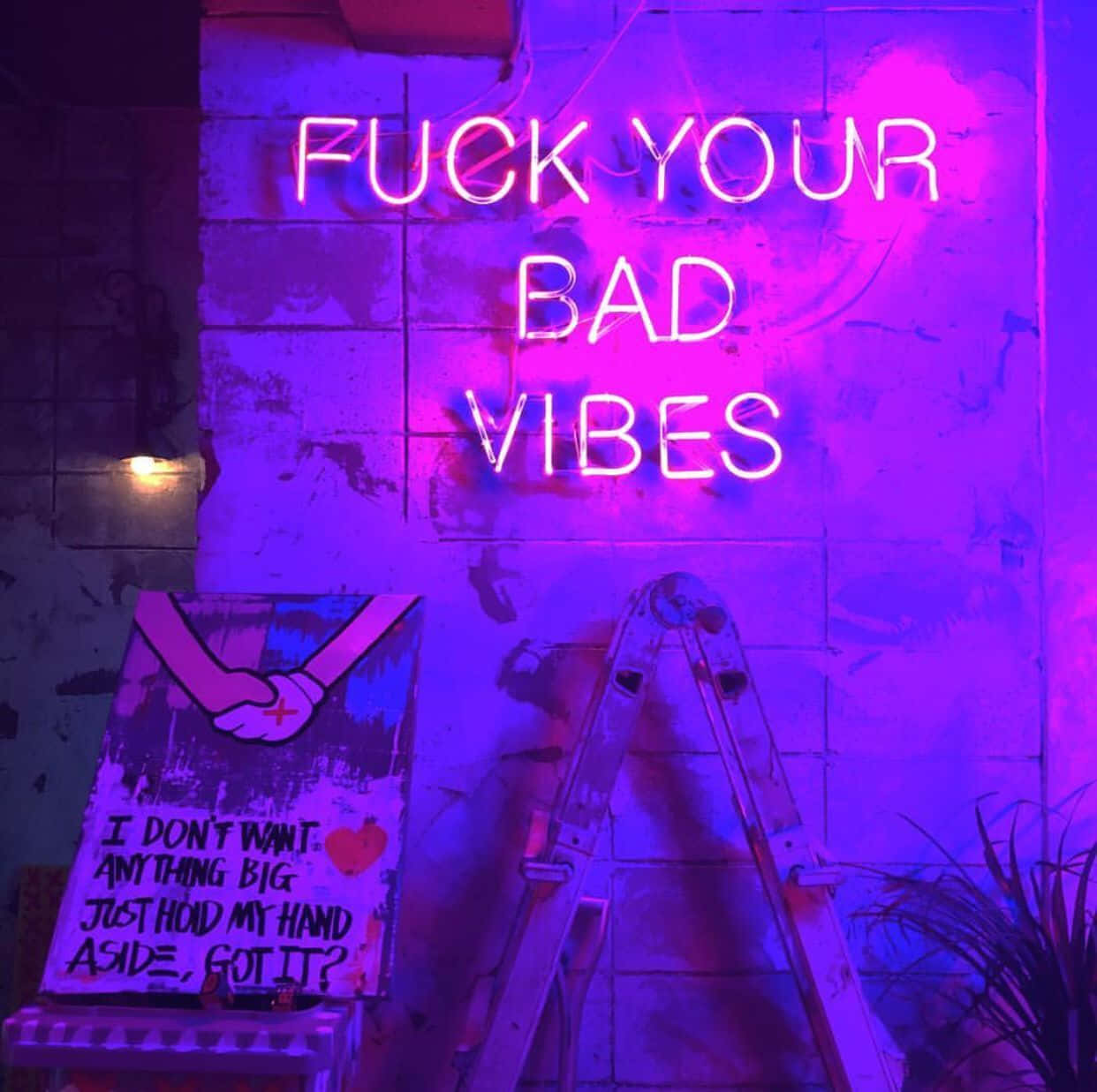 Purple Grunge Aesthetic 桌布 壁紙 — 一個寫著「FUCK YOUR BAD VIBES」的霓虹燈牌，在粉紅色和紫色中發光，掛在風化的磚牆上，旁邊有梯子和一張握手海報。