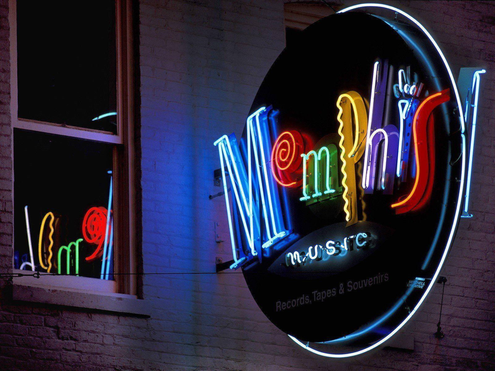 音樂 桌布 壁紙 — 一個寫著「Memphis Music」的鮮豔霓虹招牌在夜間映照著磚牆，並在窗戶上投射出色彩繽紛的倒影。