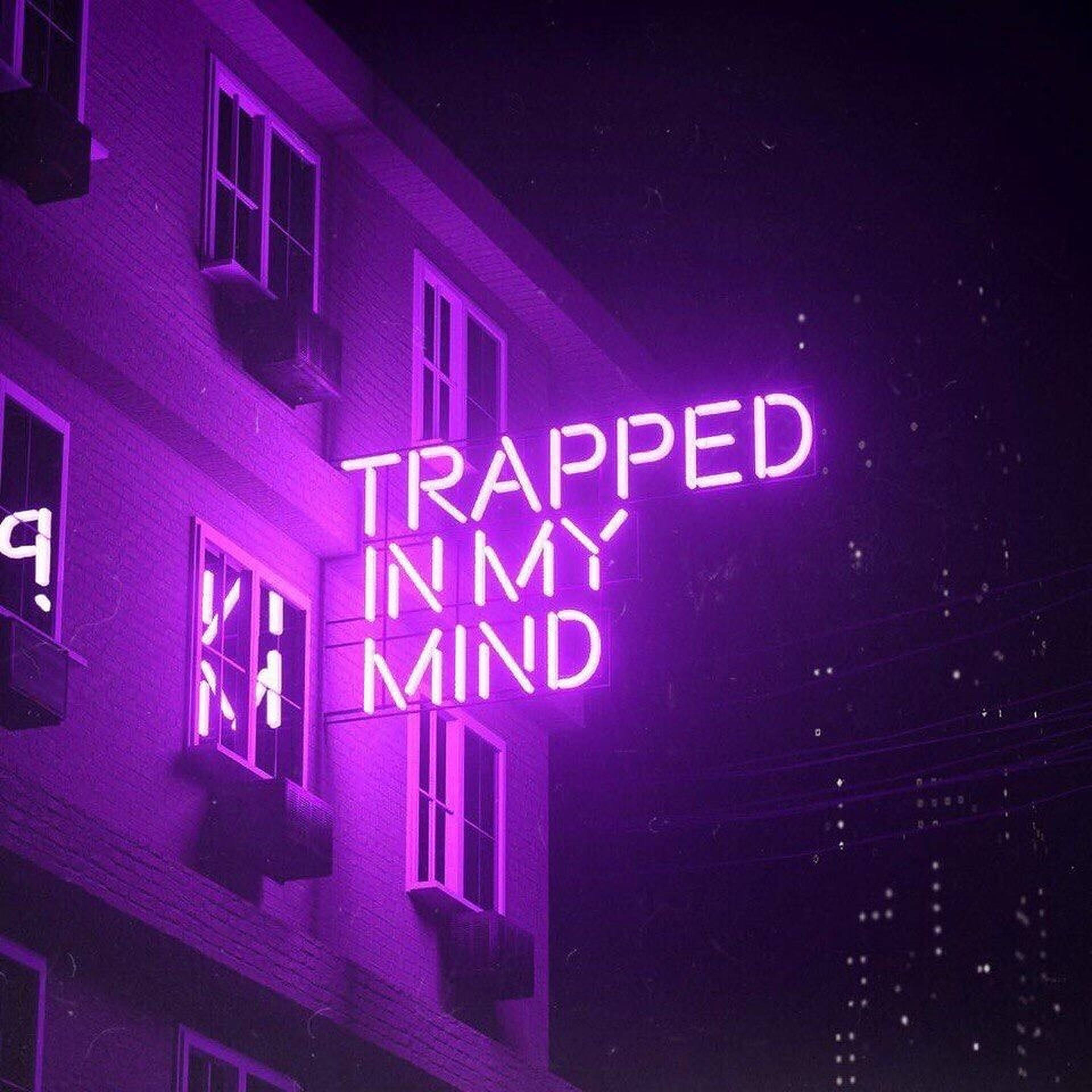 LED 桌布 壁紙 — 一個寫著 trapped in my mind 的霓虹燈牌在夜晚的磚牆上發出紫色光芒。