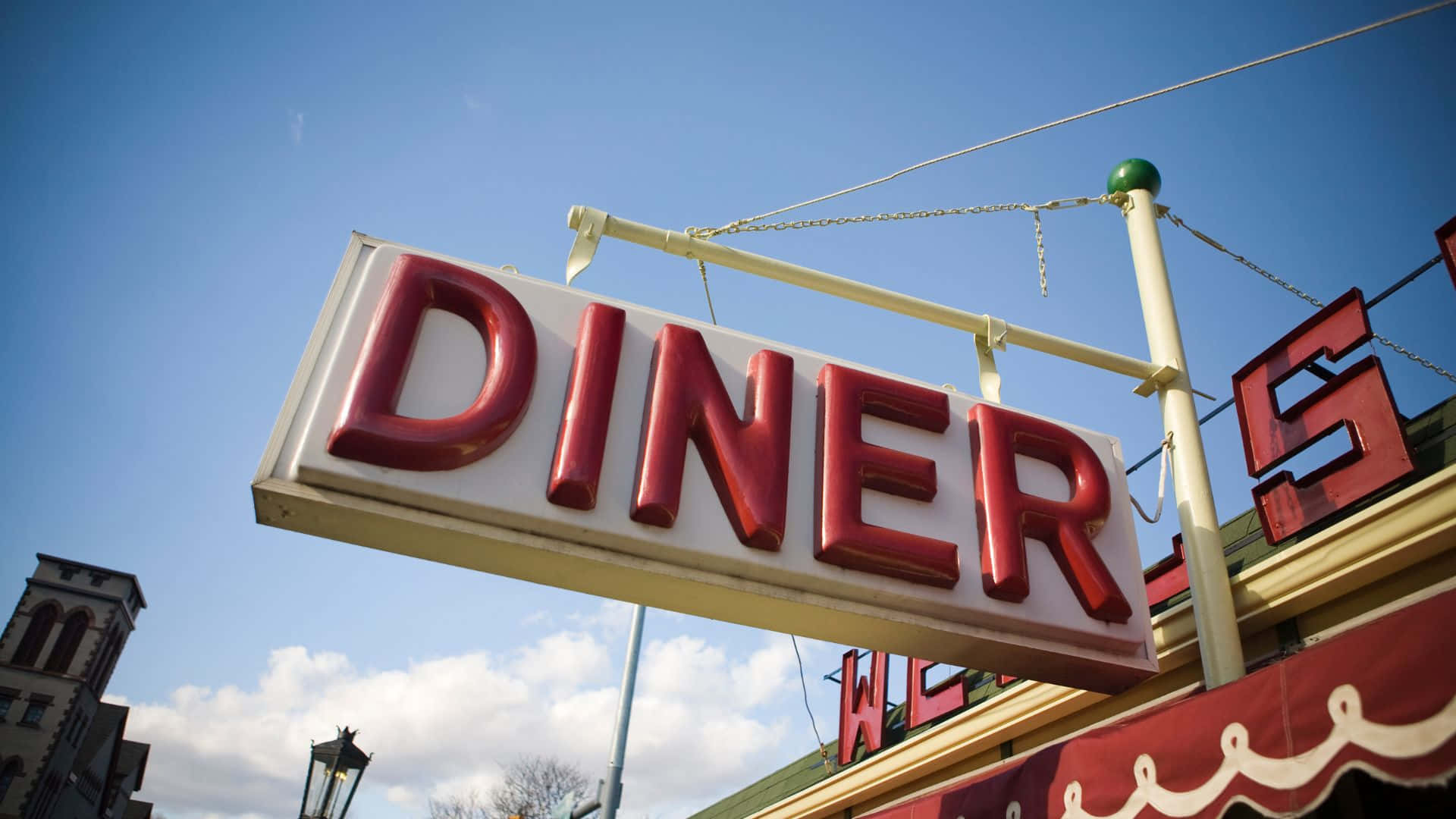 Diner 桌布 壁紙 — 一個寫著DINER的復古紅色霓虹招牌掛在藍天白雲的背景下。