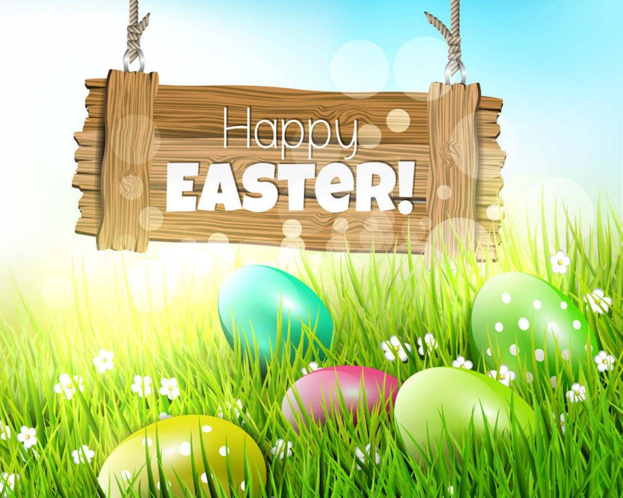 復活節 桌布 壁紙 — 一個寫著Happy Easter的木牌掛在色彩繽紛的復活蛋上方，蛋放在翠綠的草地上，伴有白色花朵。