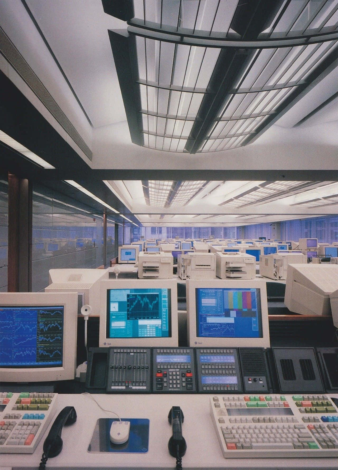 Retro Futurism 桌布 壁紙 — 一個寬敞的復古未來主義控制室，充滿一排排米色電腦工作站，在幾何天花板網格下顯示藍色數據圖表。