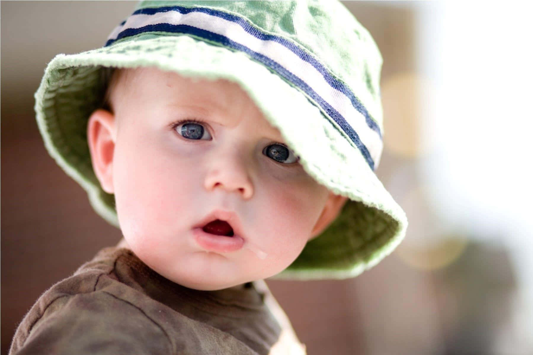 cute baby 桌布 壁紙 — 一個寶寶的特寫，戴著綠色條紋漁夫帽，眼睛睜大，嘴巴微張。