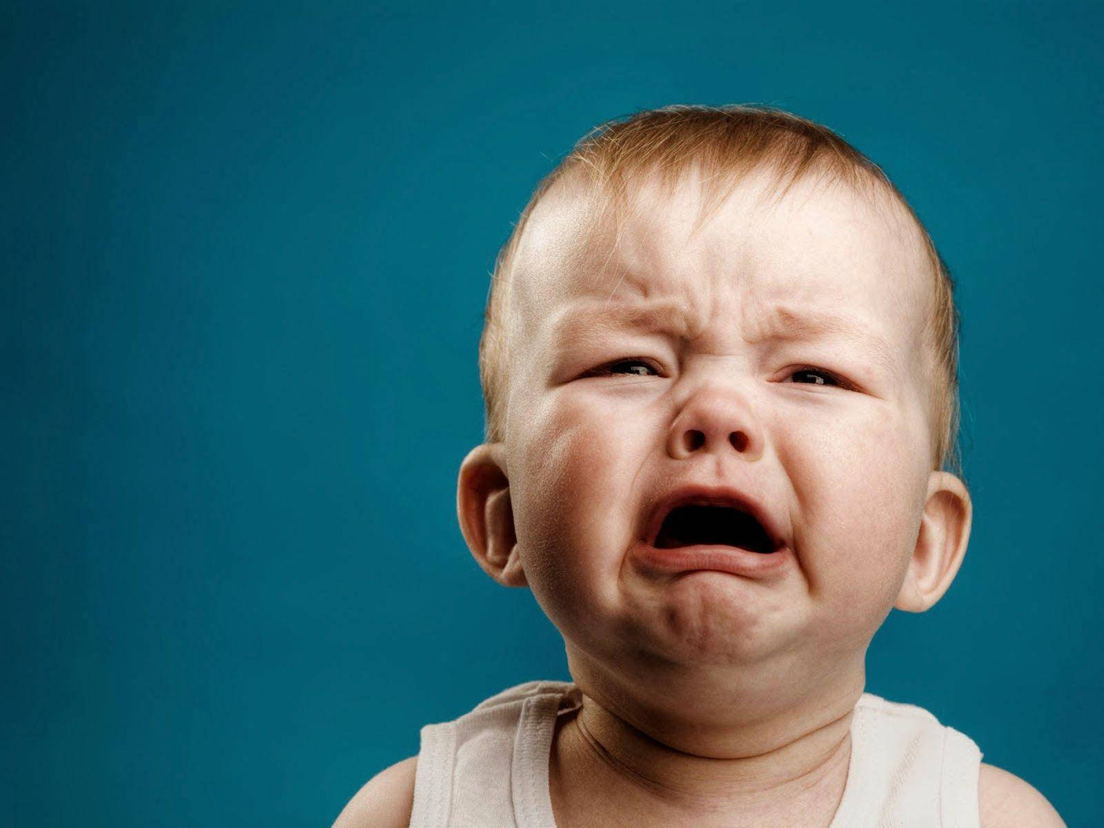 crying sad boy 桌布 壁紙 — 一個寶寶的特寫，臉頰通紅、眉頭緊皺，在純色青綠色背景前哭得很厲害。