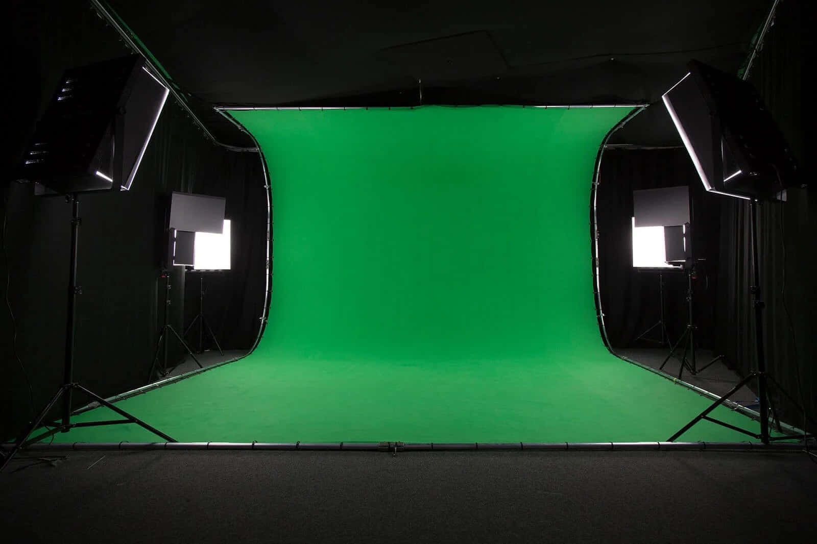 Studio 桌布 壁紙 — 一個專業的攝影棚，兩側有明亮的燈光照射著一個大型的綠幕背景。