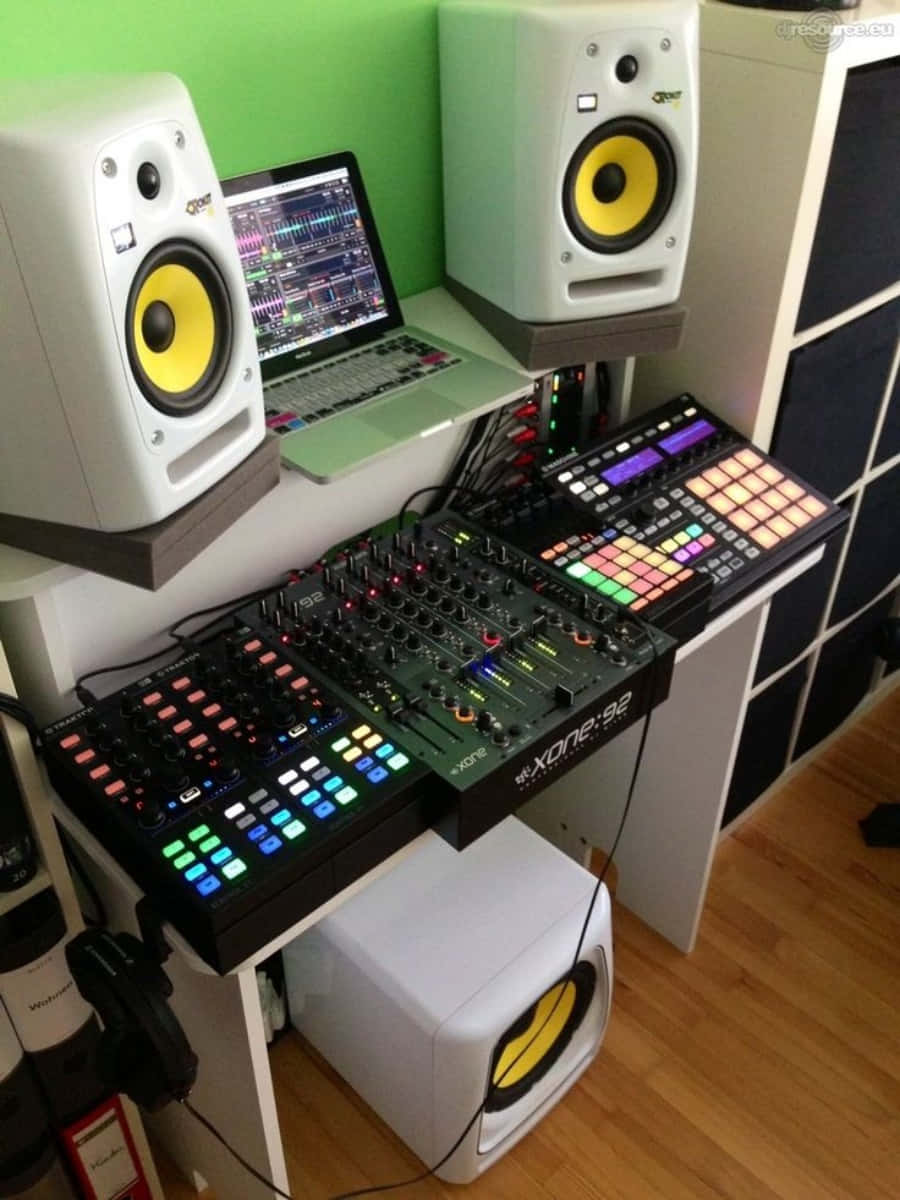 Dj Set 桌布 壁紙 — 一個專業的音樂製作設置，配有發光控制器和白色揚聲器，背景為綠色牆壁。