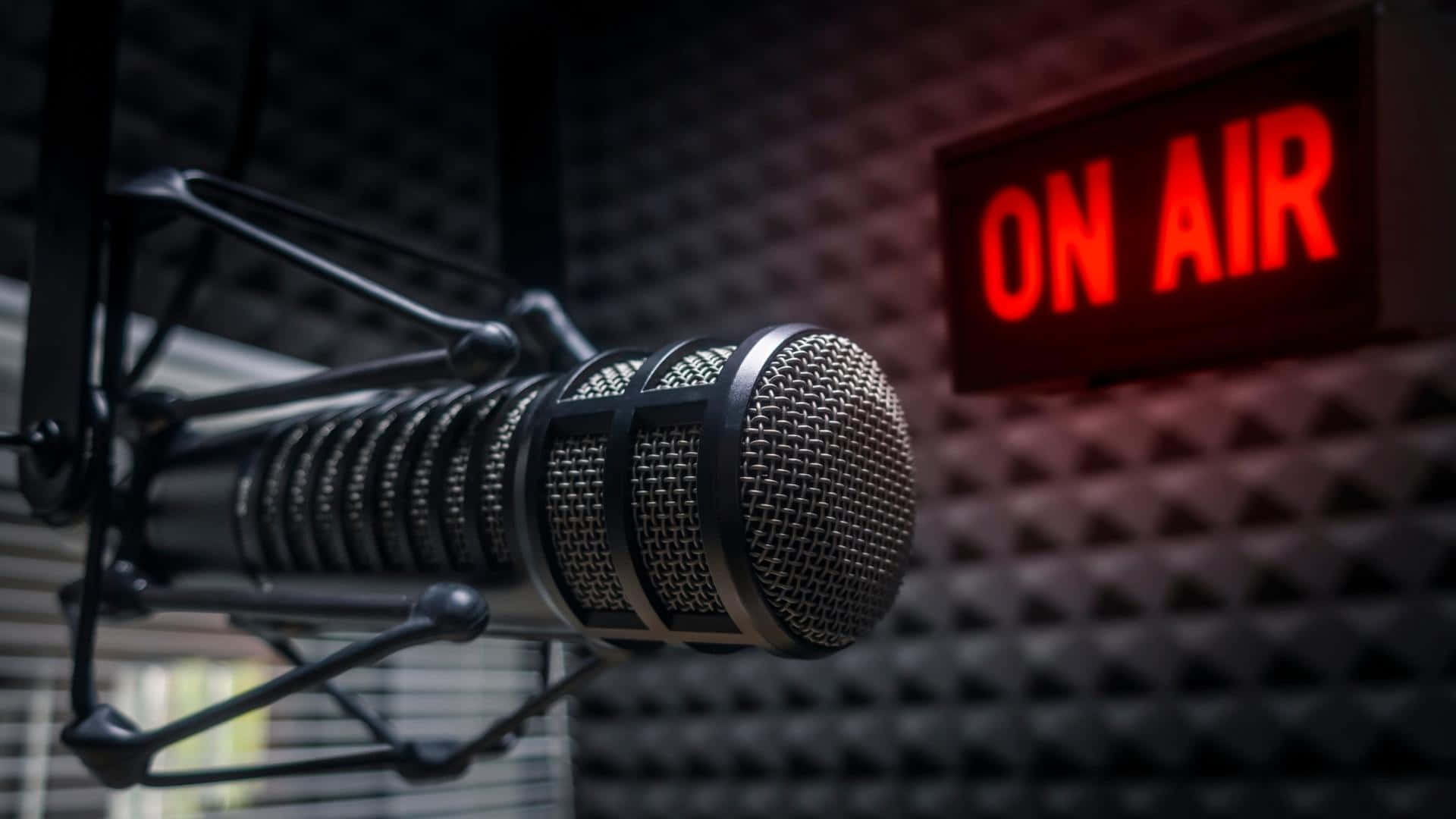 Sound 桌布 壁紙 — 一個專業錄音室麥克風懸掛在發光的紅色「ON AIR」標誌前，背景是隔音牆。