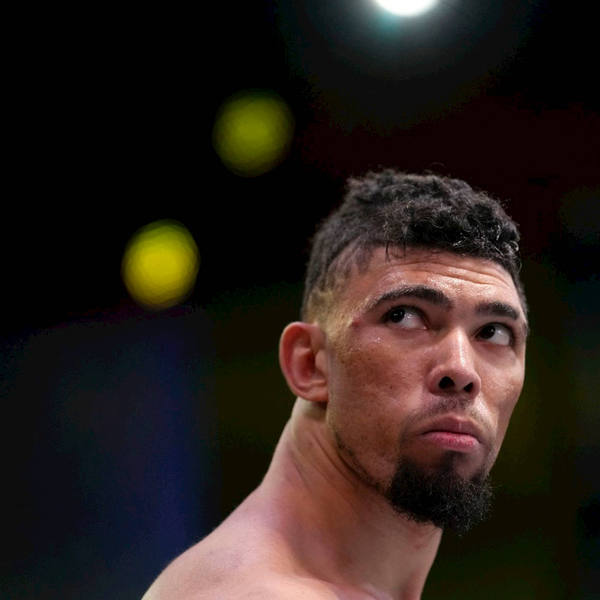 MMA 桌布 壁紙 — 一個專注的戰士，鬍鬚和汗水在競技場燈光下閃閃發光，背景黑暗模糊。