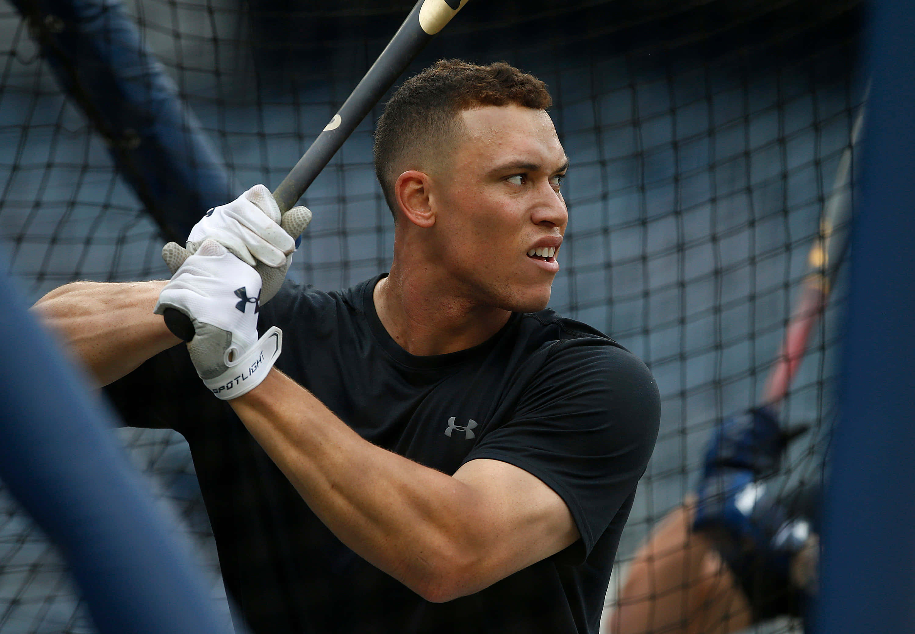 MLB Players 桌布 壁紙 — 一個專注的棒球選手在打擊籠中，在揮棒中途用力握住球棒，集中力極高。