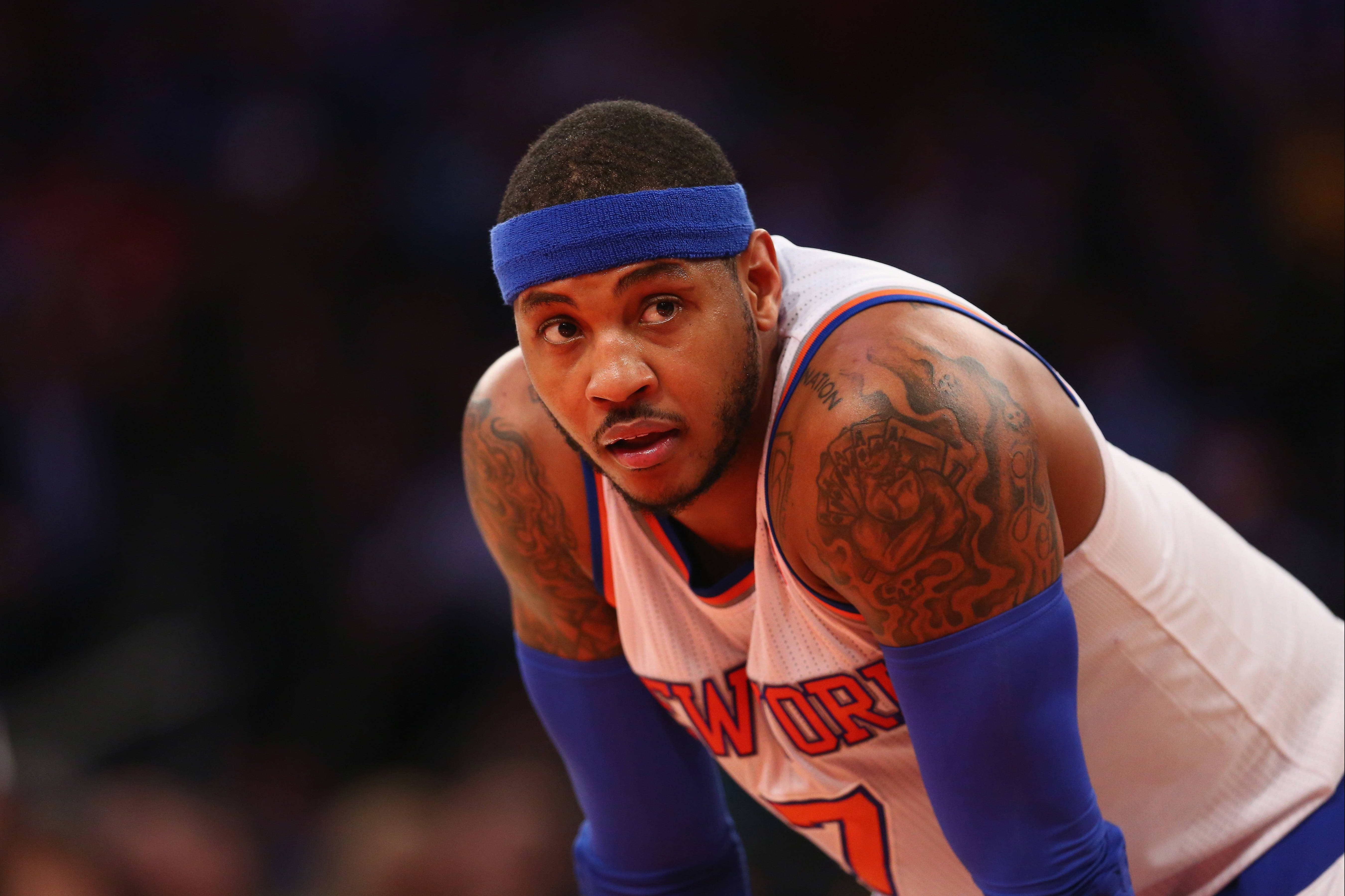 Carmelo 桌布 壁紙 — 一個專注的籃球運動員，身上有刺青，戴著藍色頭帶，身體前傾，處於比賽準備姿勢。