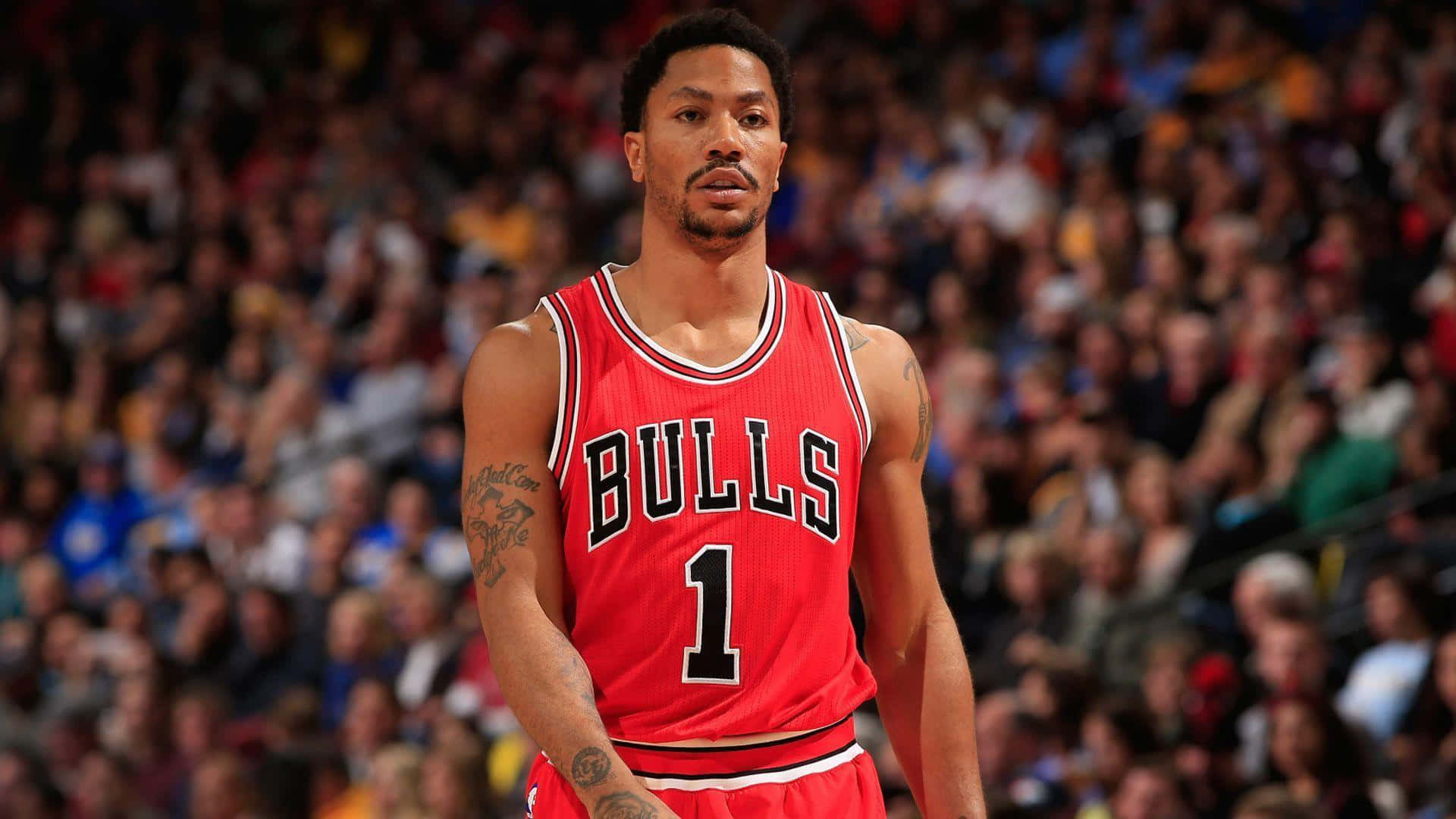 derrick rose 桌布 壁紙 — 一個專注的籃球運動員穿著紅色公牛隊球衣站在球場上，身後是模糊的人群。