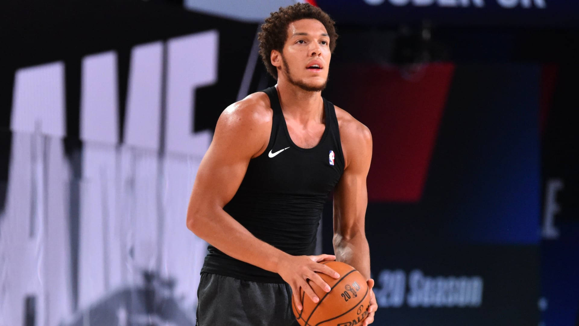 aaron gordon 桌布 壁紙 — 一個專注的籃球運動員穿著黑色背心，在明亮的場館燈光下於比賽中持球。