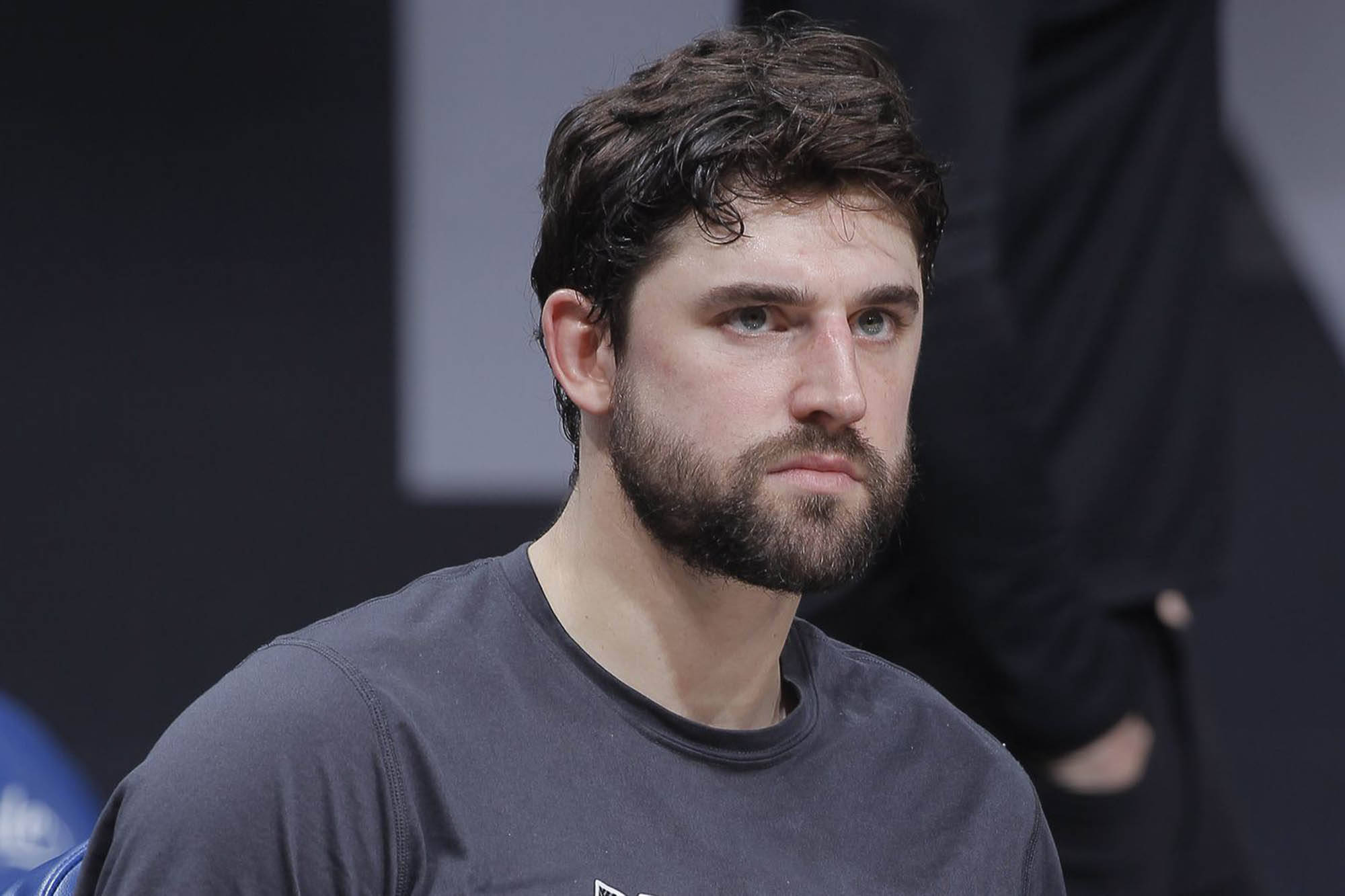 joe harris 桌布 壁紙 — 一個專注的鬍鬚男穿著深灰色T恤，在模糊的室內背景下帶著嚴肅的表情專注地凝視。