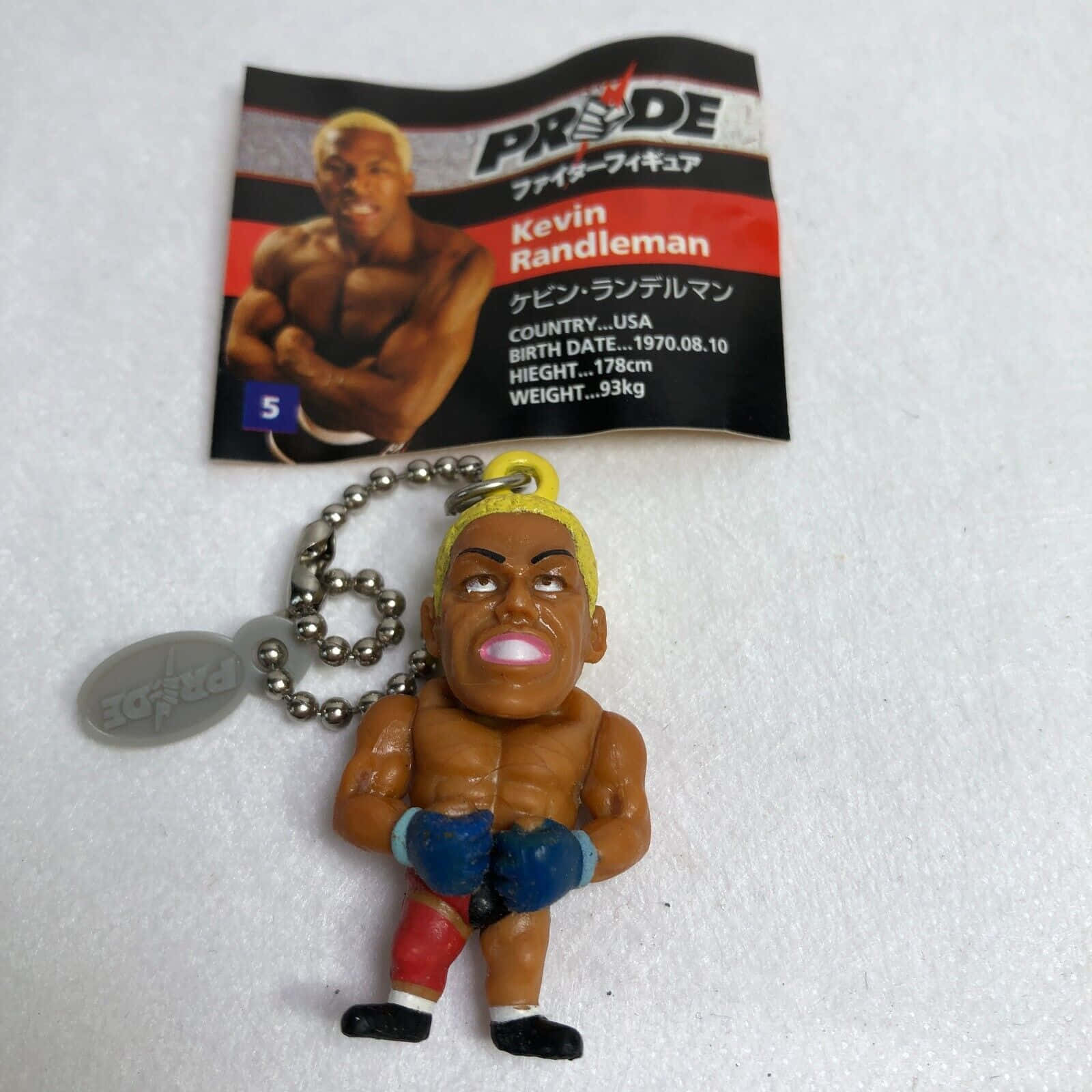 UFC 桌布 壁紙 — 一個小型塑膠格鬥家Kevin Randleman人偶用球鏈掛在其品牌包裝旁邊的白色表面上。