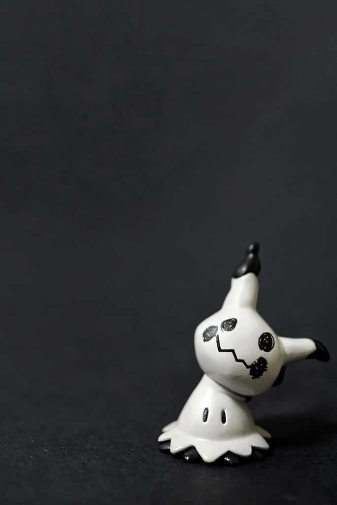 Pokemon Figures 桌布 壁紙 — 一個小型白色幽靈般的寶可夢公仔，有黑色眼睛和鋸齒狀嘴巴，站在深色紋理背景前。