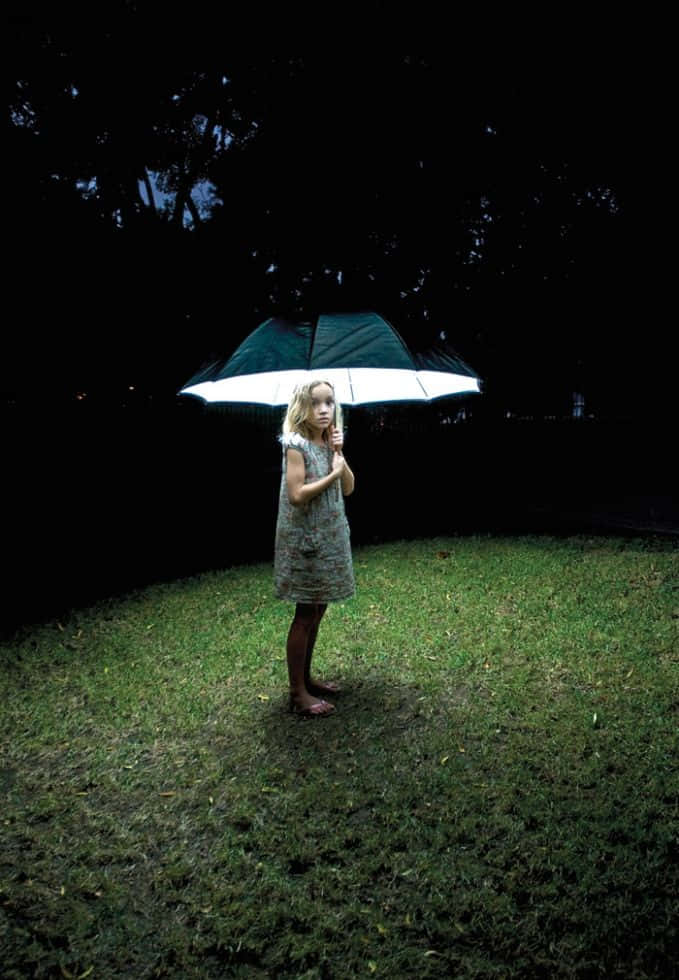 Umbrella 桌布 壁紙 — 一個小女孩獨自站在黑暗的庭院中，在夜空下拿著一把發光的雨傘。