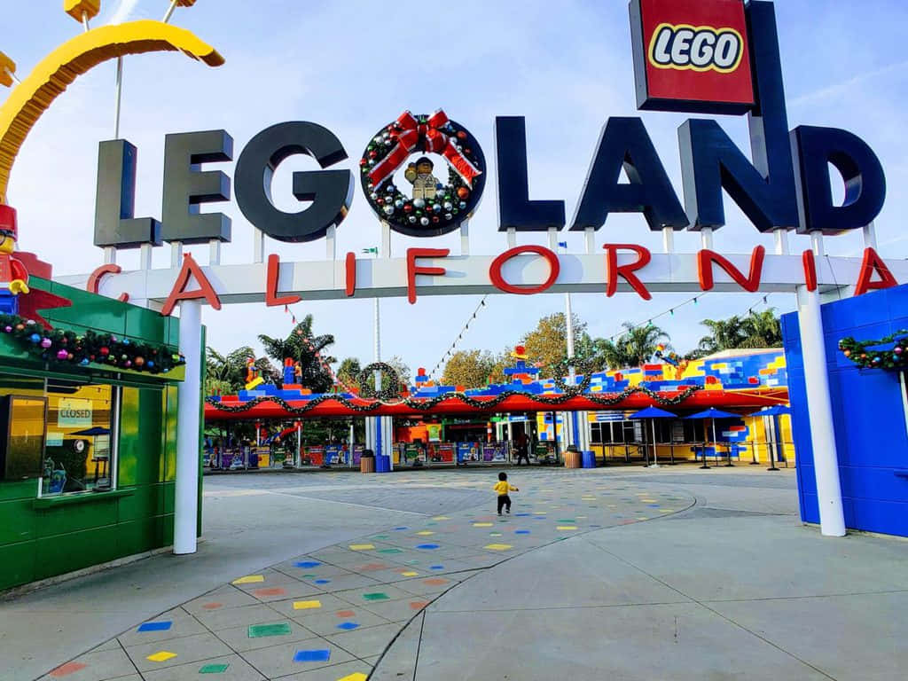 Legoland 桌布 壁紙 — 一個小孩走向色彩繽紛的LEGO Land California入口，入口在晴朗的藍天下裝飾著節日裝飾。