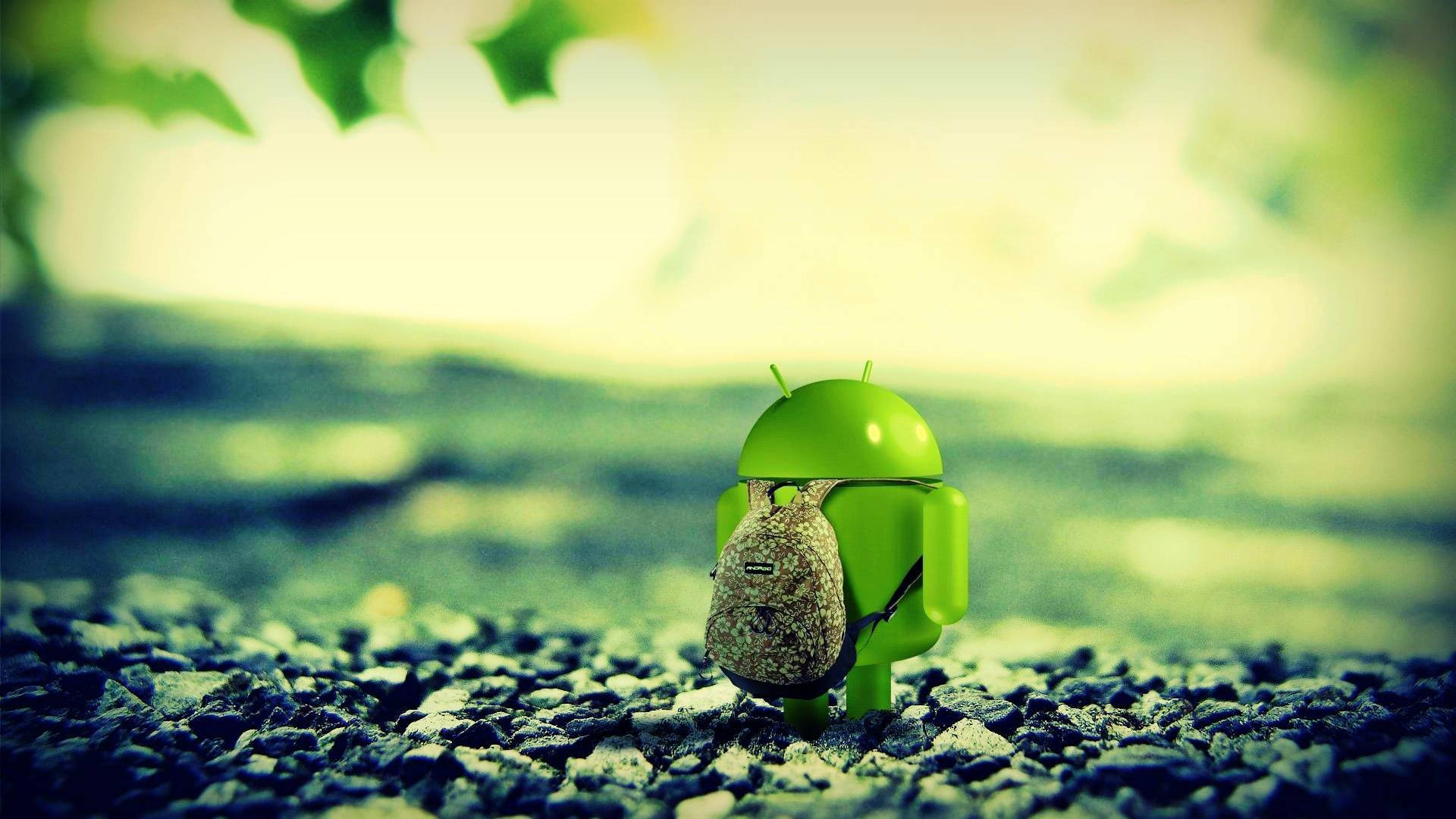 full HD tablet 桌布 壁紙 — 一個小小的綠色Android公仔背著背包，站在碎石路上，上方有柔和的陽光和模糊的樹葉。