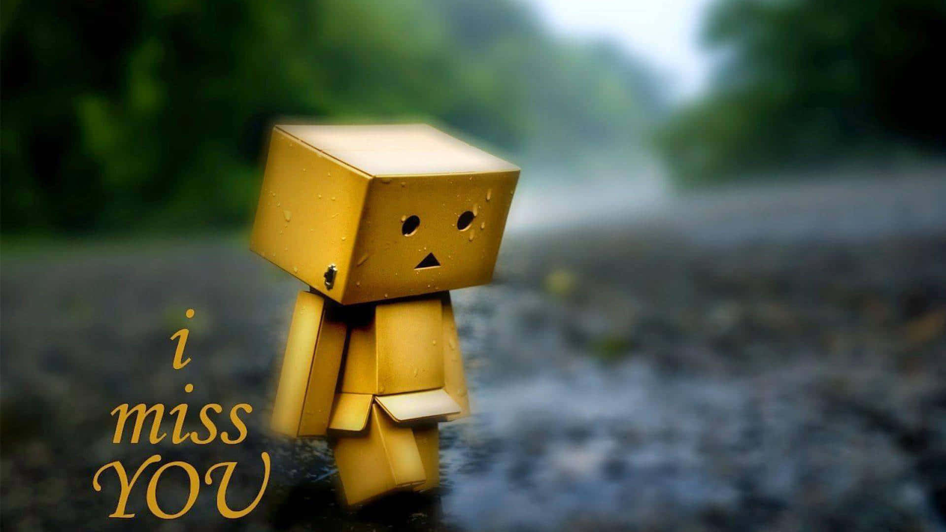 我想你 桌布 壁紙 — 一個小小的黃色紙箱角色獨自站在雨中潮濕的小路上，背景是模糊的綠色森林。