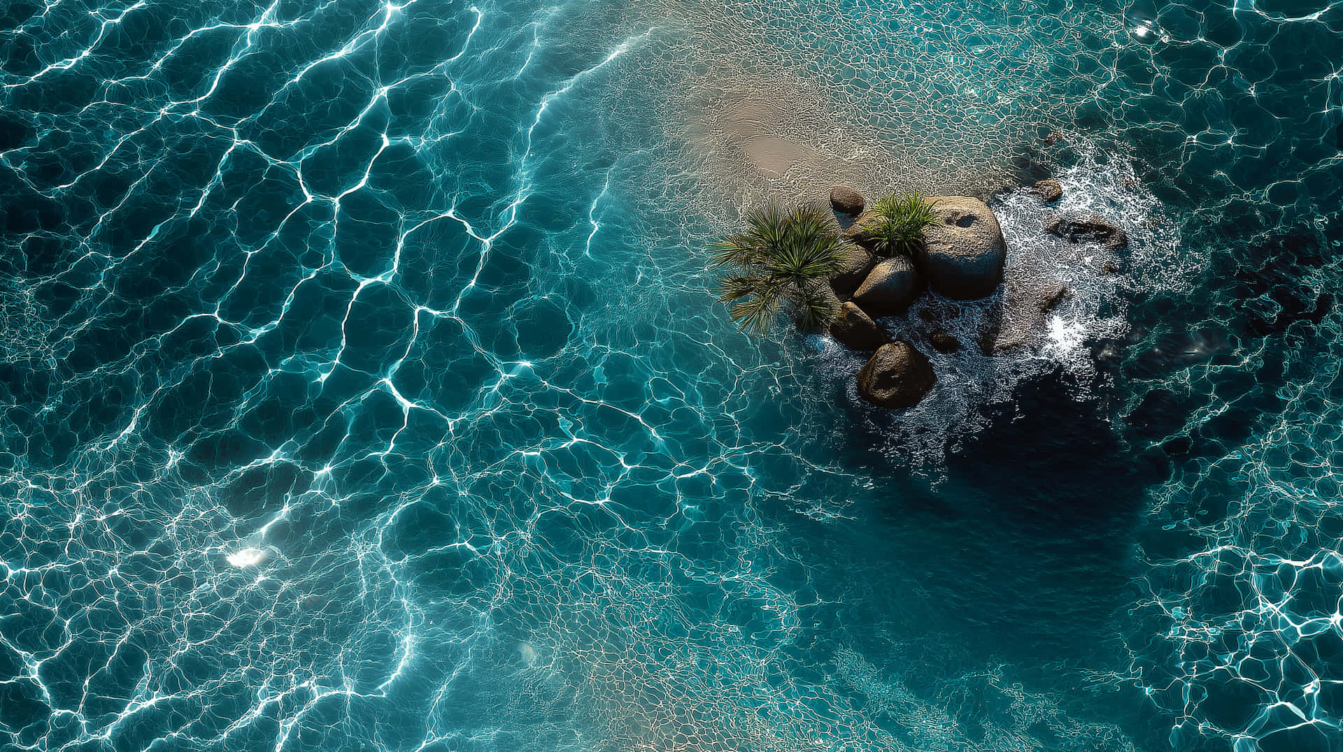 Clear Sea Water from Above, Pure Aquatic Background 壁紙 — 一個小岩石島嶼的鳥瞰圖，島上有棕櫚樹，周圍是碧綠的海水，帶有明亮的陽光反射。