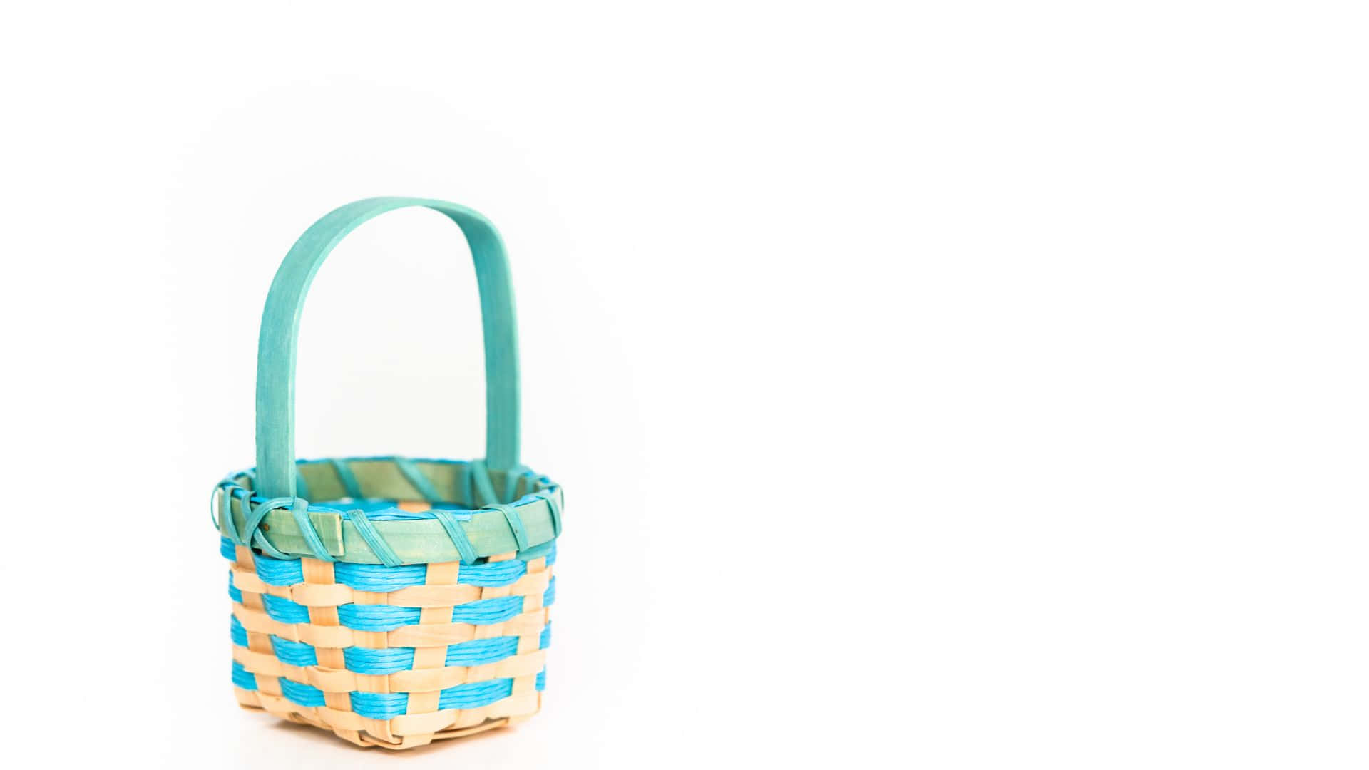 Easter Basket 桌布 壁紙 — 一個小巧的編織籃，帶有淺色木材和綠松石藍色點綴，孤立在純白色背景上。