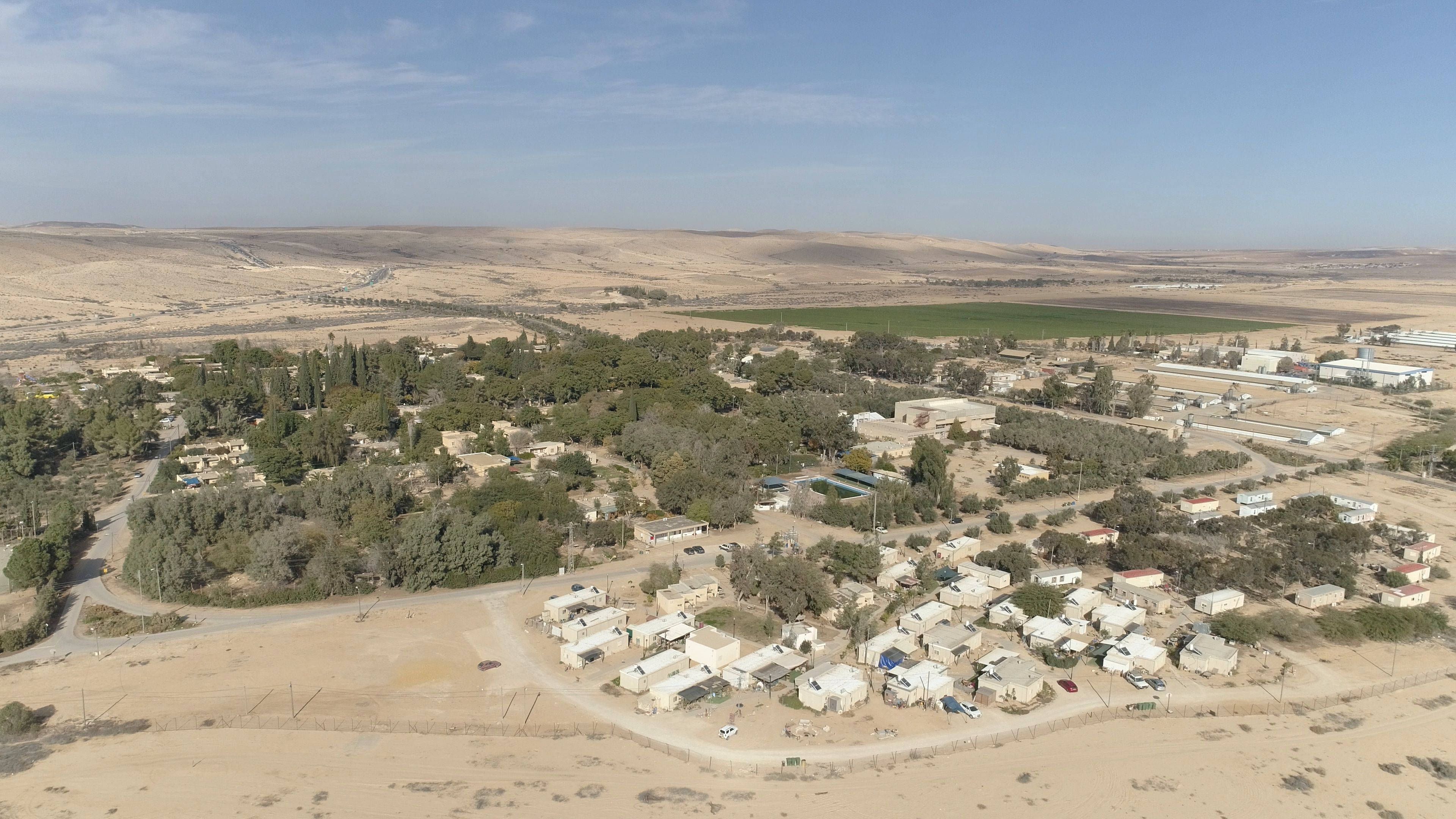 Israel 桌布 壁紙 — 一個小沙漠村莊的鳥瞰圖，散落著房屋和綠色田野，在晴朗的藍天下。