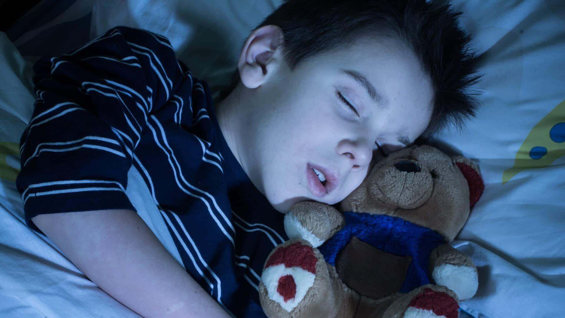 Sleep 桌布 壁紙 — 一個小男孩在冰冷的藍色燈光下抱著泰迪熊在床上安睡。