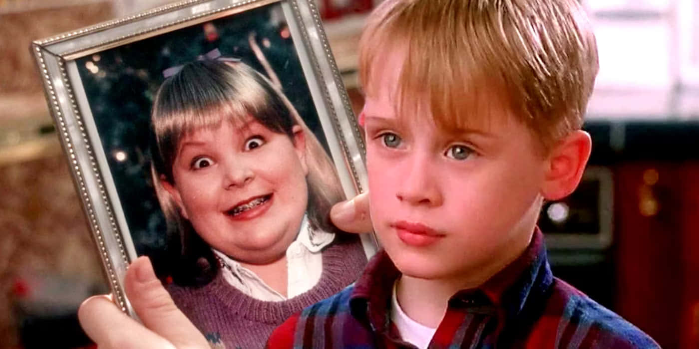 Home Alone 桌布 壁紙 — 一個小男孩拿著一個微笑女孩的相框照片，女孩有大眼睛和紫色毛衣。