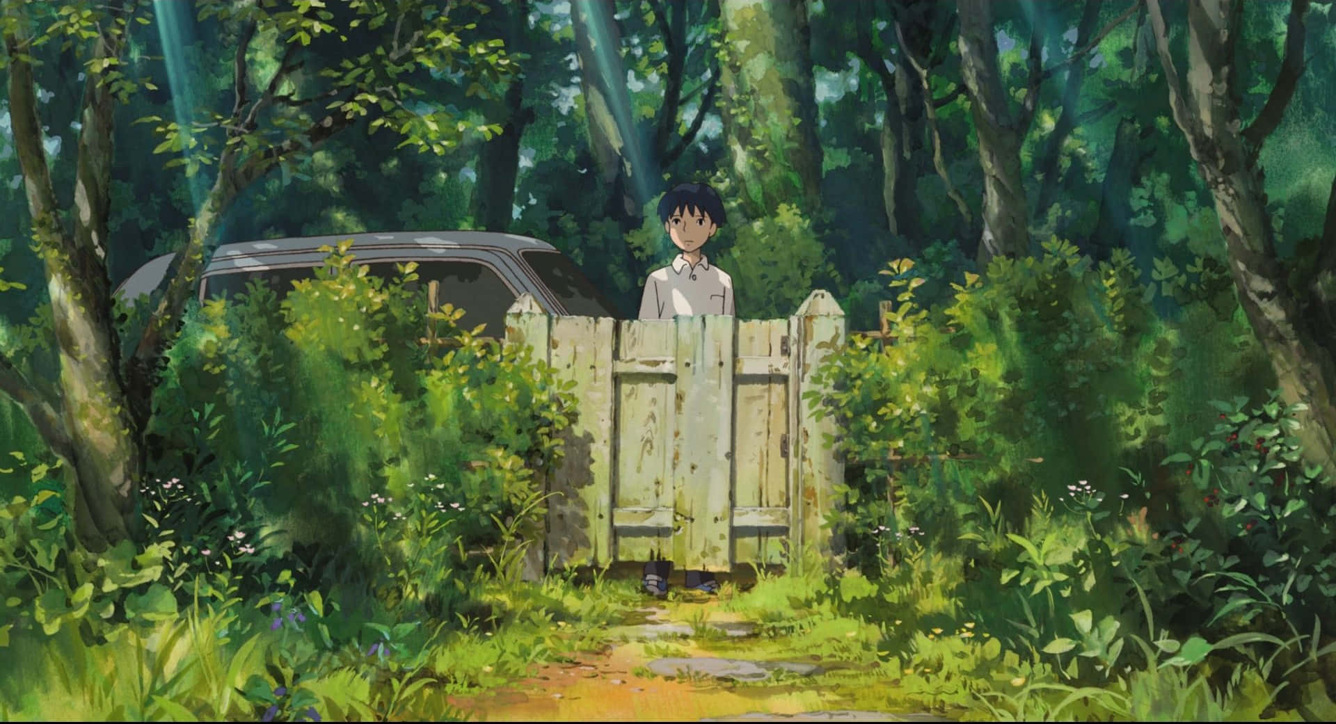 The Secret World Of Arrietty 桌布 壁紙 — 一個小男孩站在一扇風化的木門後面，身處陽光斑駁的森林中，周圍是茂密的綠色樹葉，身後隱約可見一輛復古汽車。