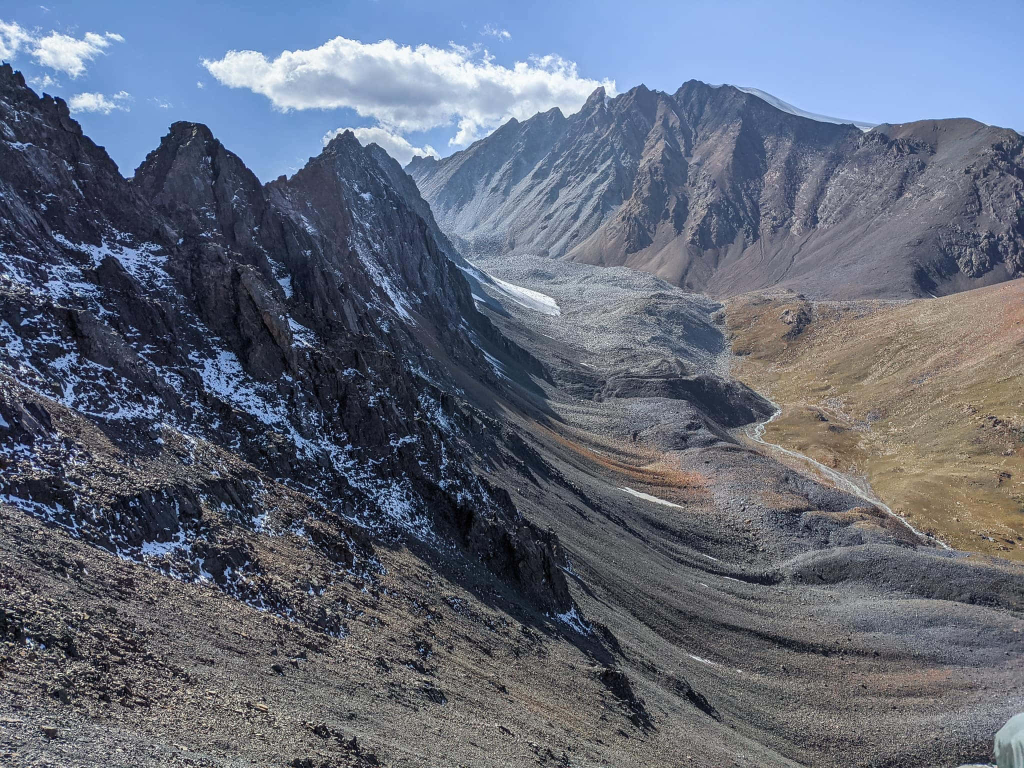 Mountain Landscape 桌布 壁紙 — 一個崎嶇的山谷，有白雪覆蓋的山峰和蜿蜒的河流，在明亮的藍天和散落的雲朵下。