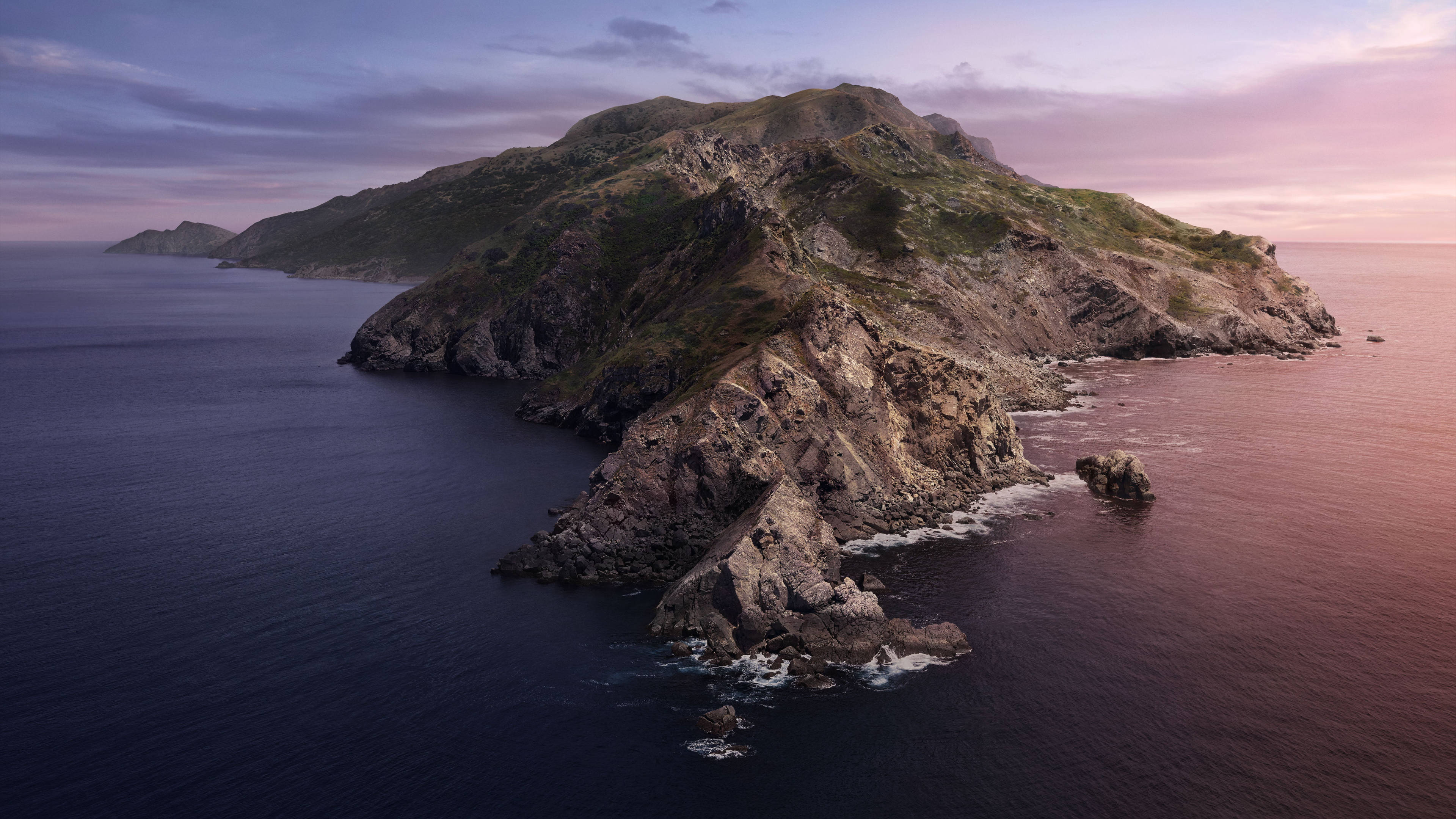 島嶼 桌布 壁紙 — 一個崎嶇的島嶼，有岩石峭壁和綠色斜坡，從深藍色的海水中升起，在柔和的粉紅色和紫色暮色天空下。