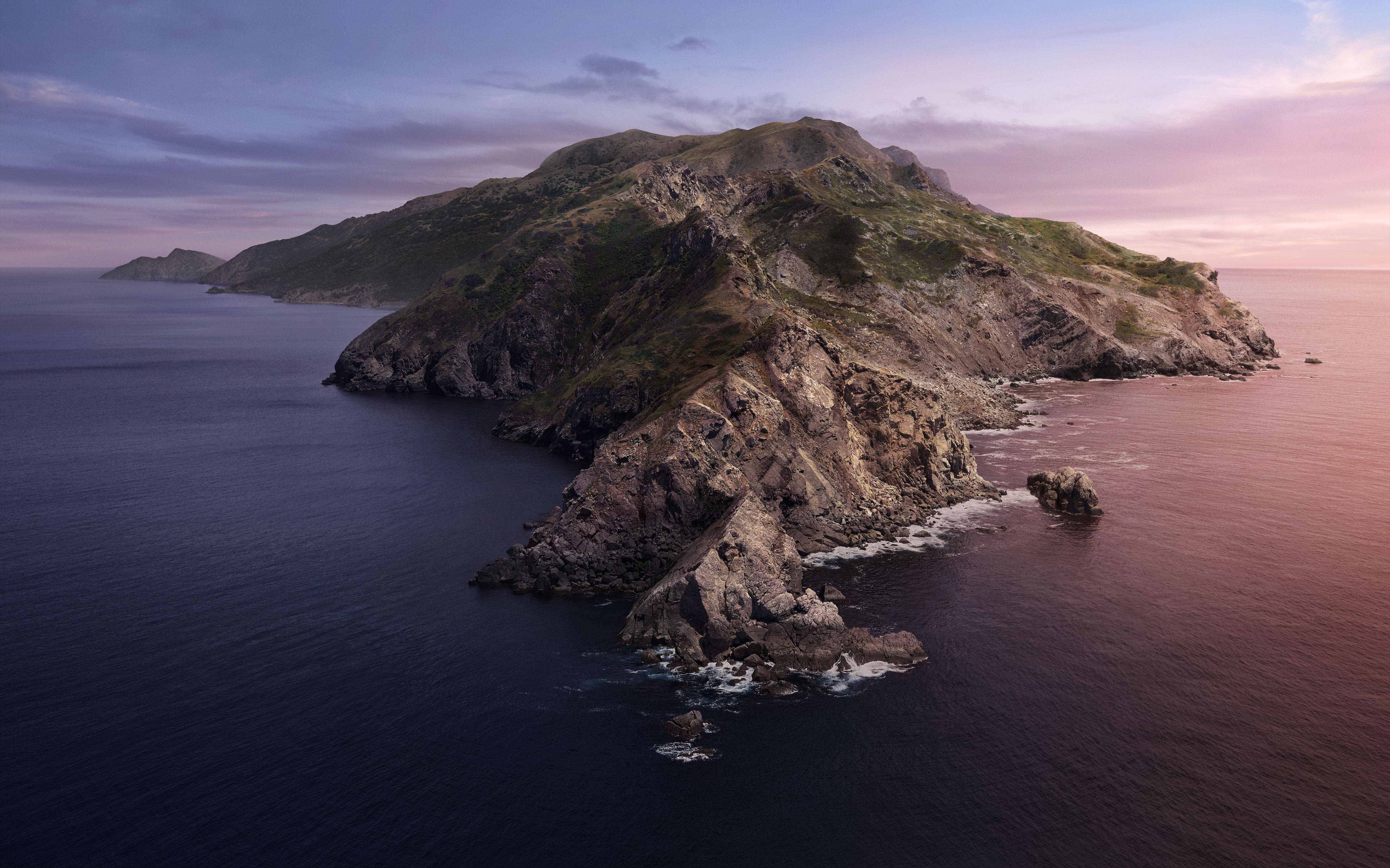 Catalina 桌布 壁紙 — 一個崎嶇的島嶼，長滿青草的山峰和岩石海岸沐浴在柔和粉紅和紫色的暮色中，平靜的海水之上。