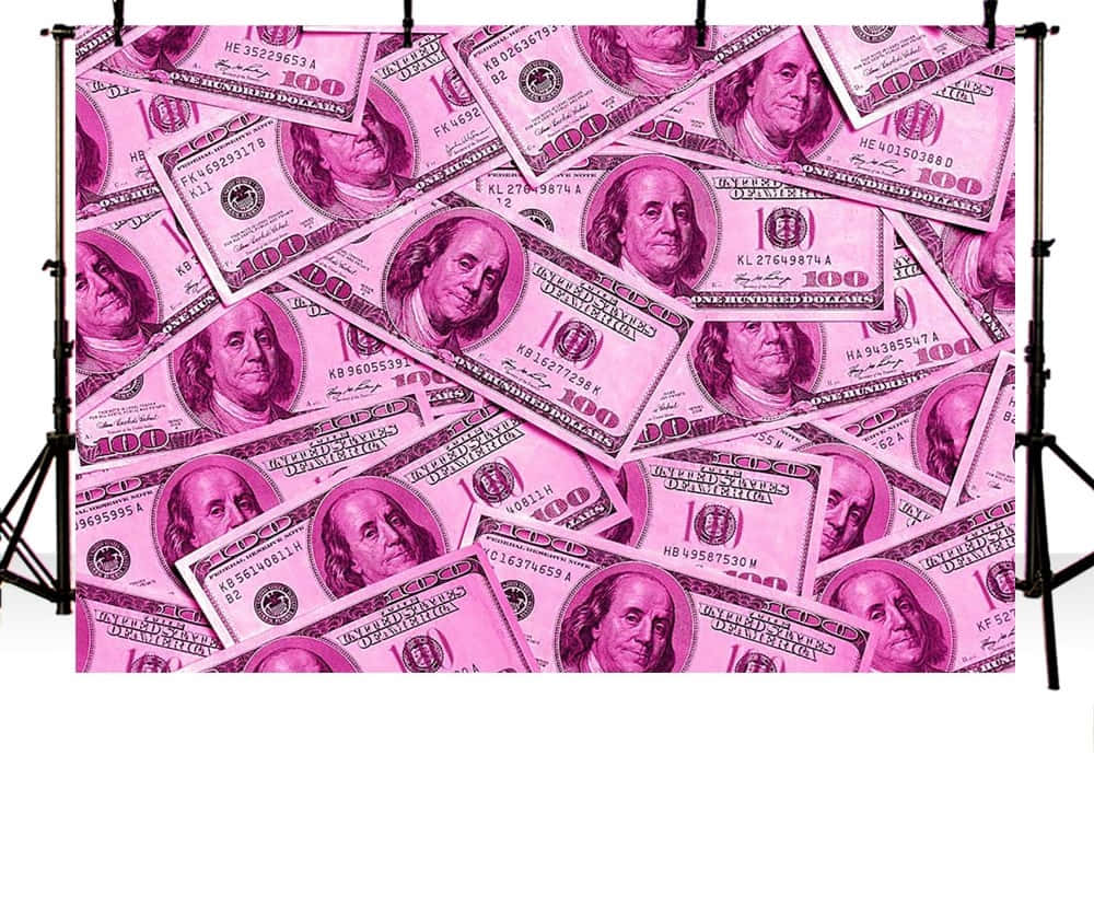 Pink Money 桌布 壁紙 — 一個工作室背景，上面鋪滿了粉紅色調的百元美鈔，雜亂地堆疊在一起。